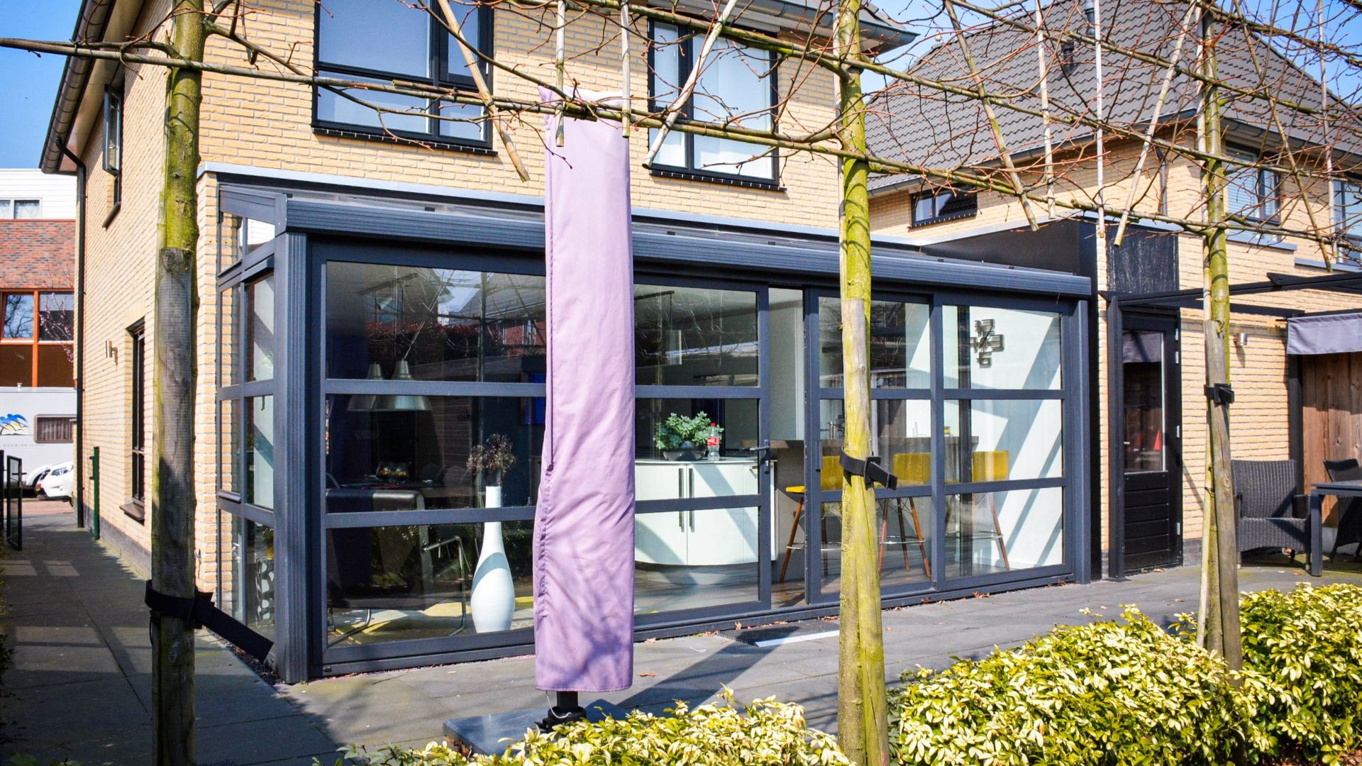 Moderne serre met steellook kozijnen en glazen schuifwanden aan woning