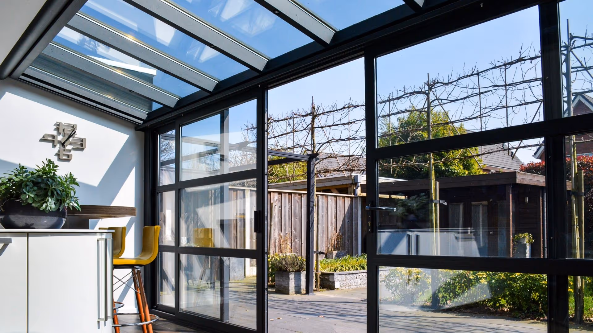 Steellook schuifdeur en glazen serre met zicht op moderne tuin in Hengelo