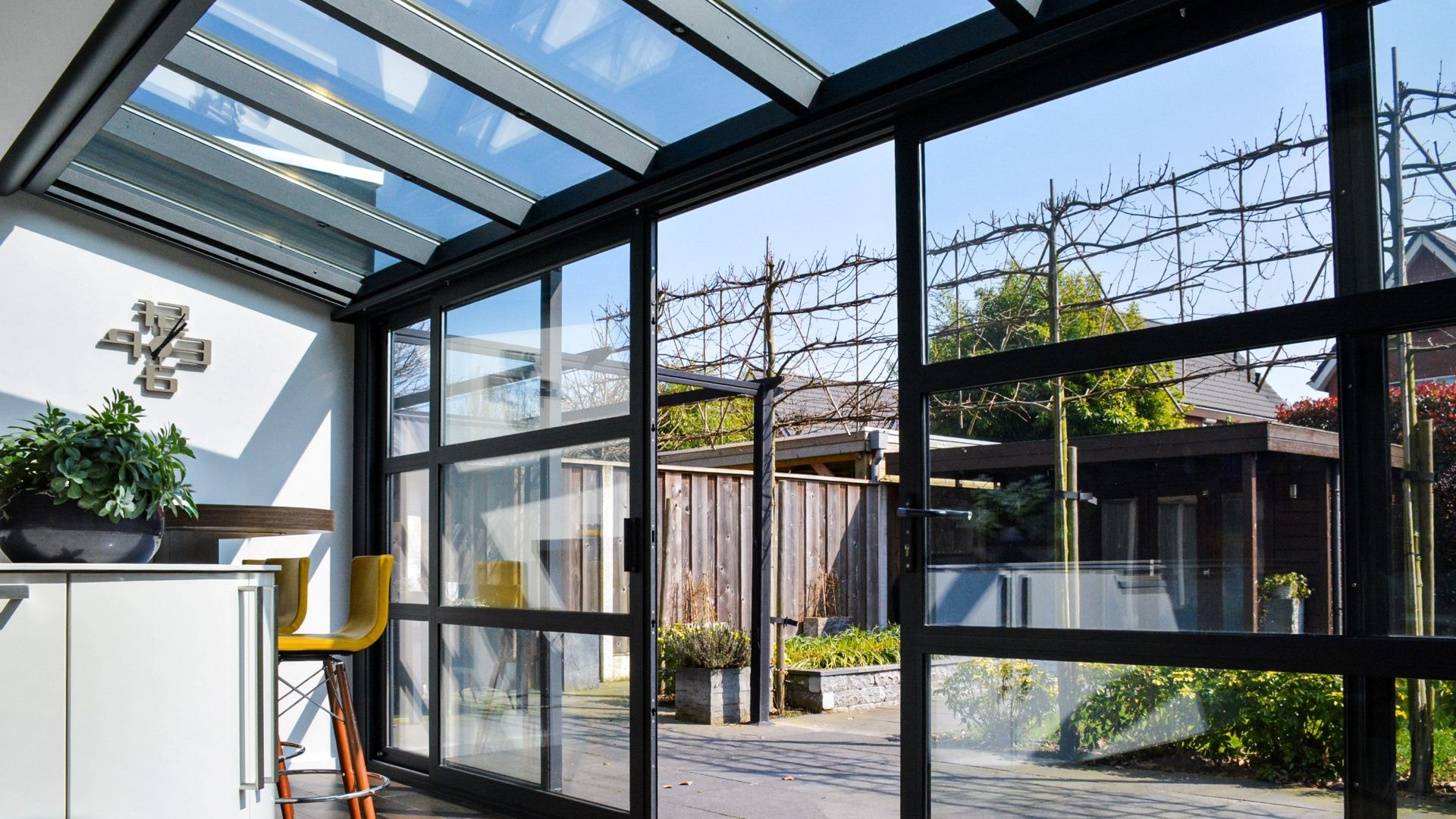 Steellook schuifdeur en glazen serre met zicht op moderne tuin in Hengelo