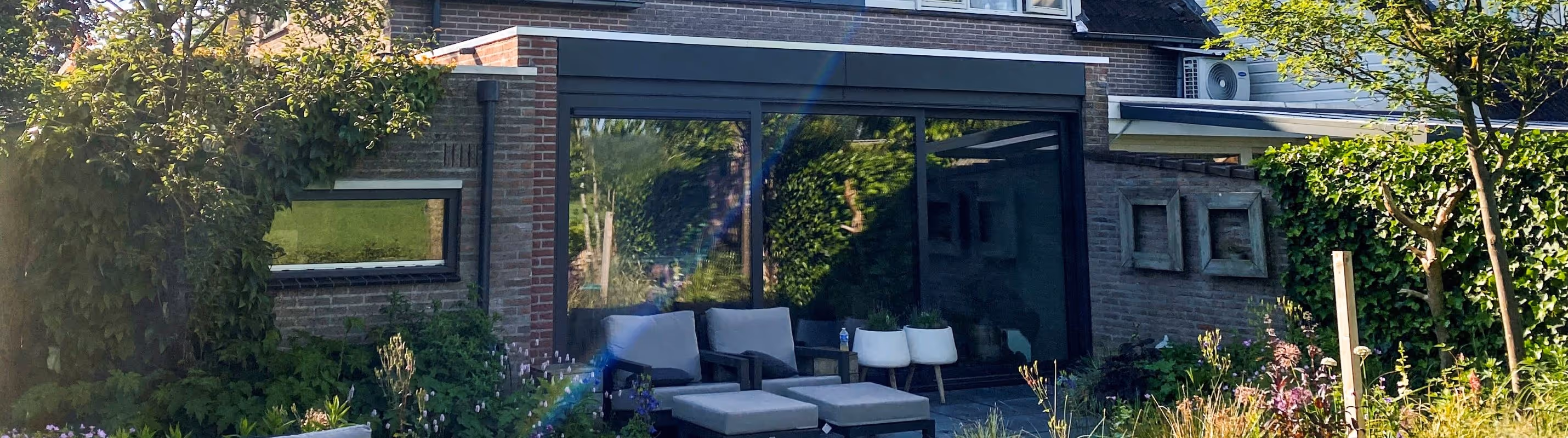 Serre uitbouw Borculo Luxe serre aan woning met zwarte aluminium kozijnen en moderne tuin
