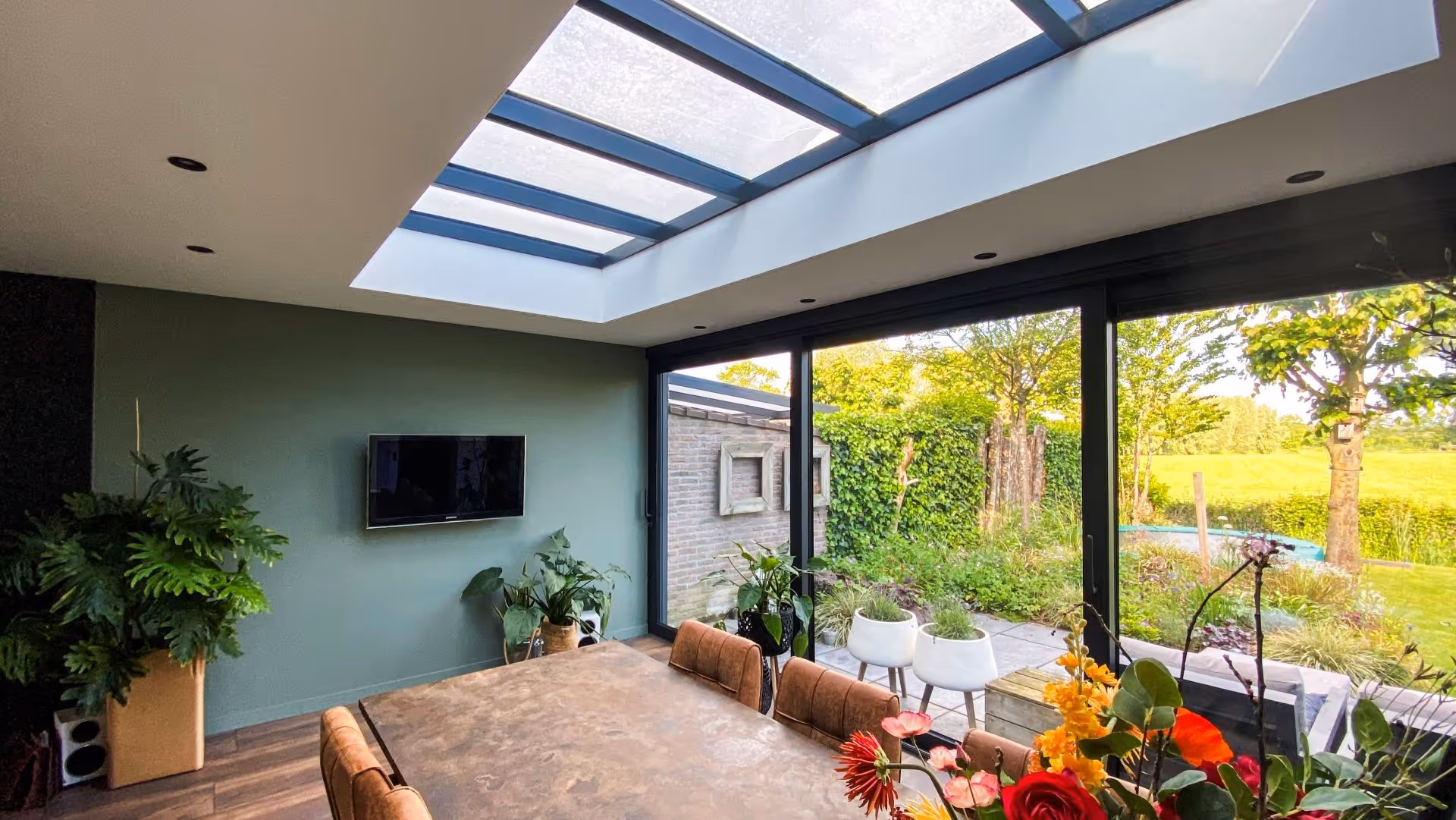 Moderne leefserre met aluminium kozijnen en panoramisch uitzicht op groene tuin