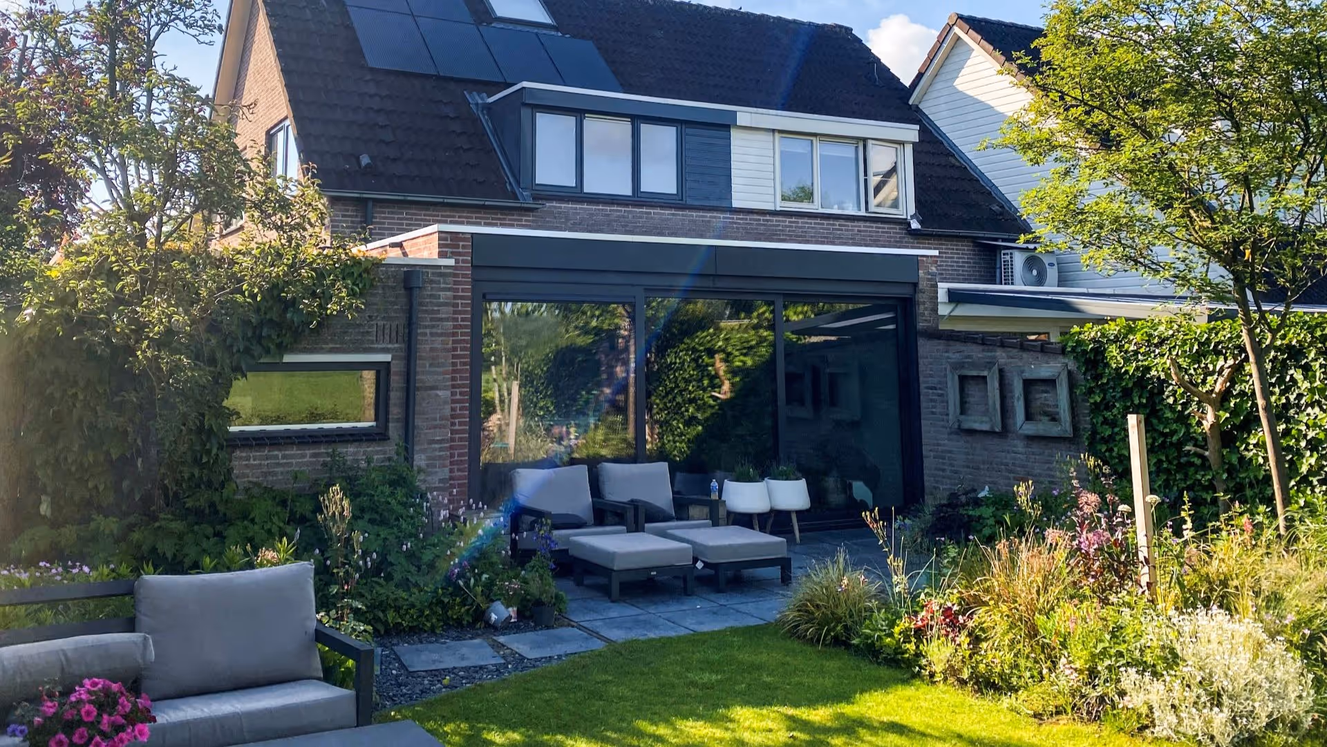 Moderne serre uitbreiding met veel glas en stijlvolle tuin aan woning in Borculo