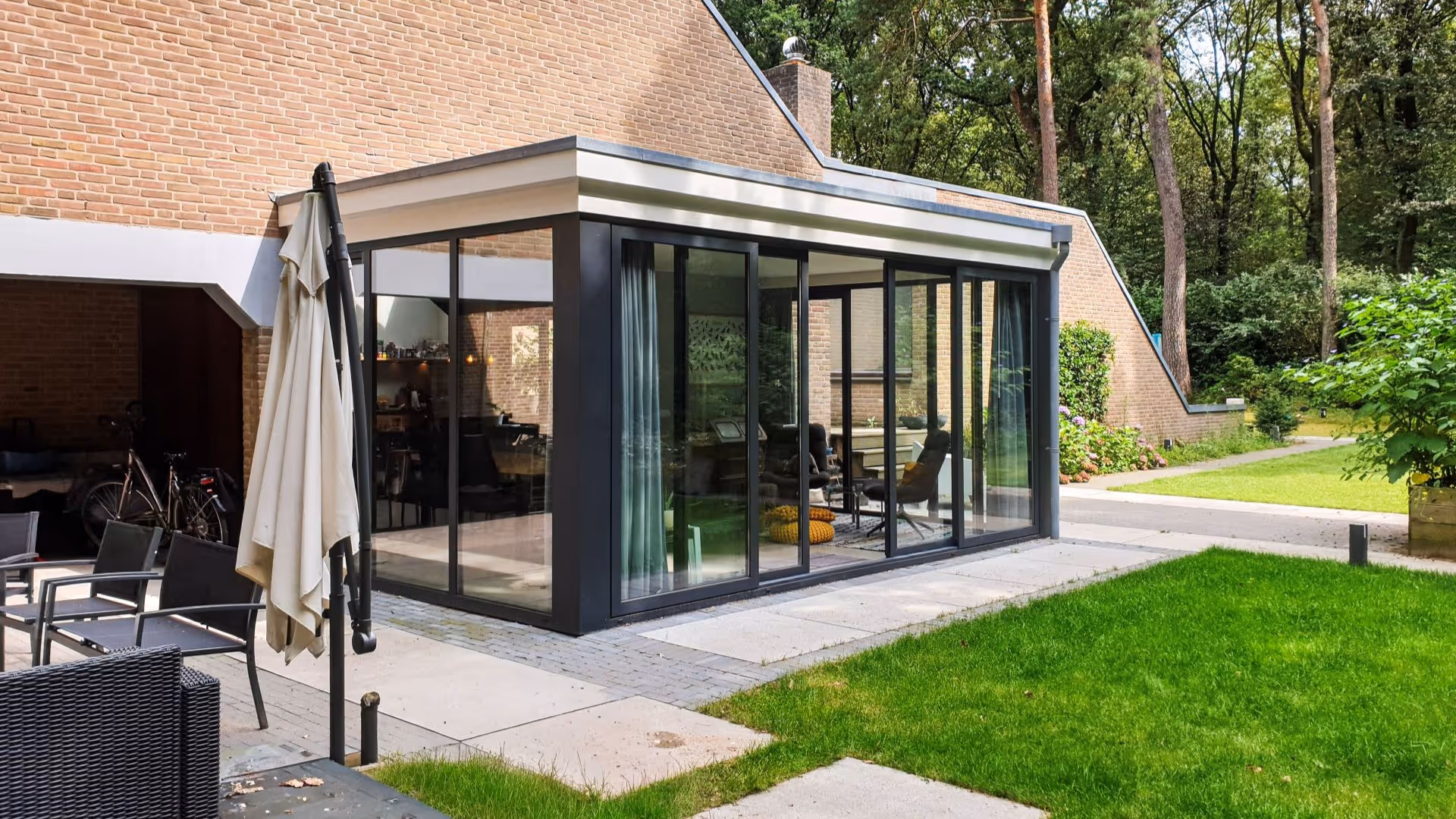 Strakke aluminium serre met panoramisch tuinzicht en hoogwaardige glazen schuifdeuren