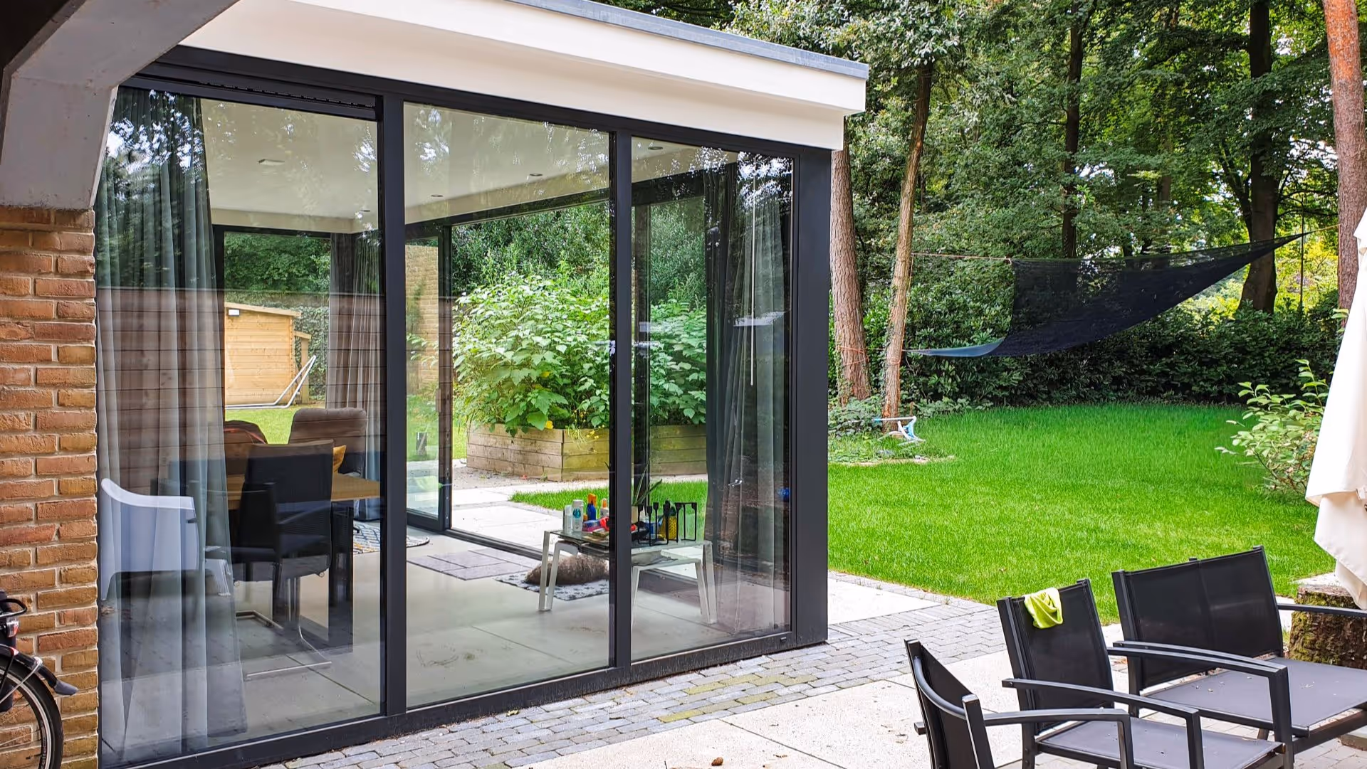 Luxe aluminium serre met grote glazen schuifpuien en vrij uitzicht op groene tuin in Doorwerth