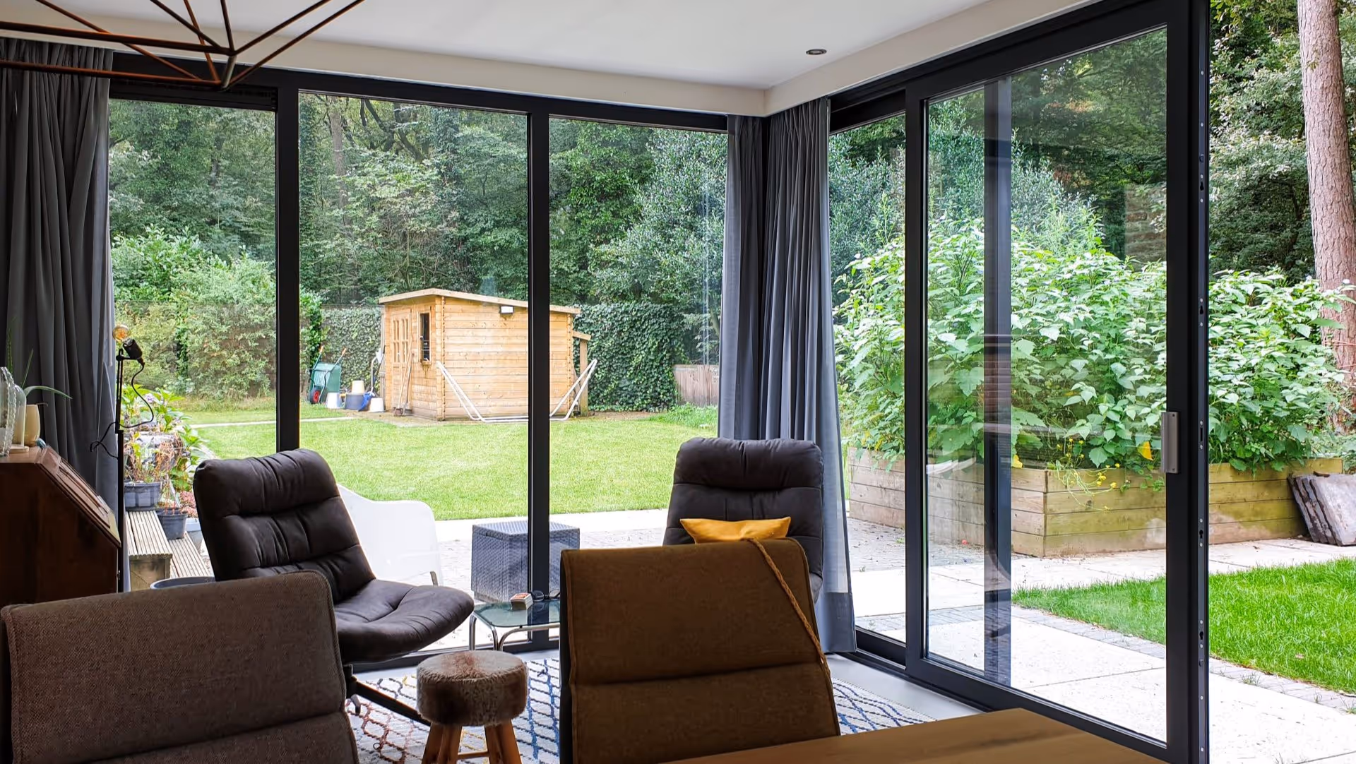 Moderne leefserre met veel daglicht en comfortabele zithoek aan groene bostuin