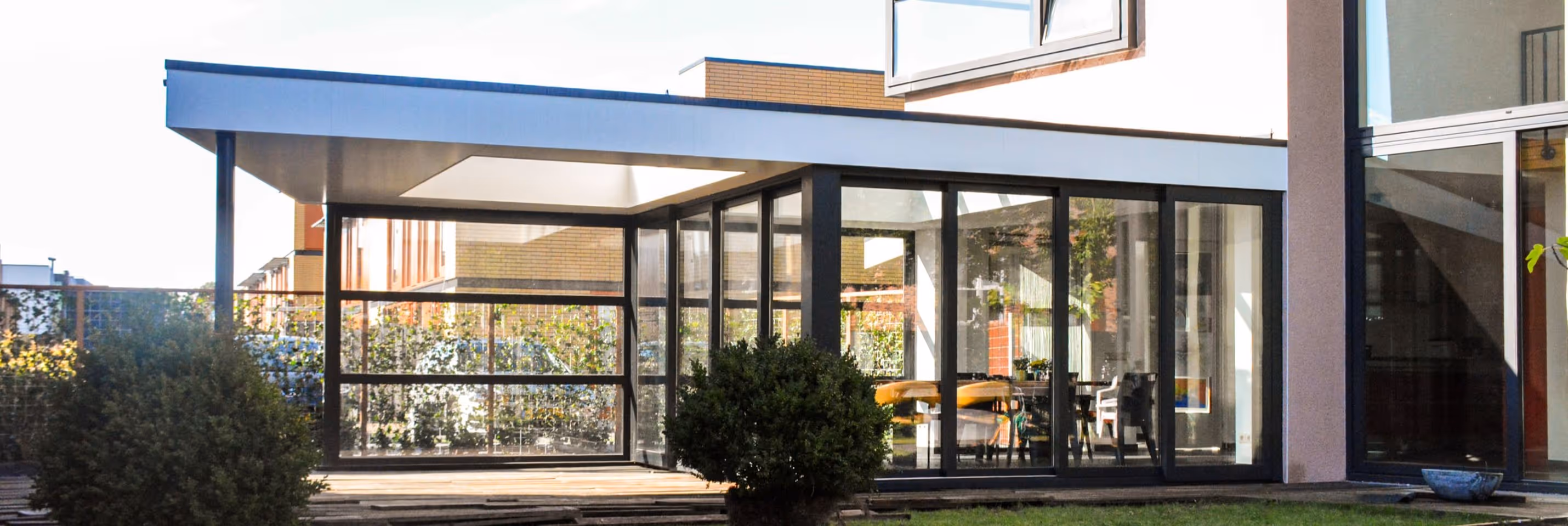 Serre uitbouw Vijfhuizen - Strakke aluminium serre aan moderne woning met overkapping en grote glaspartijen