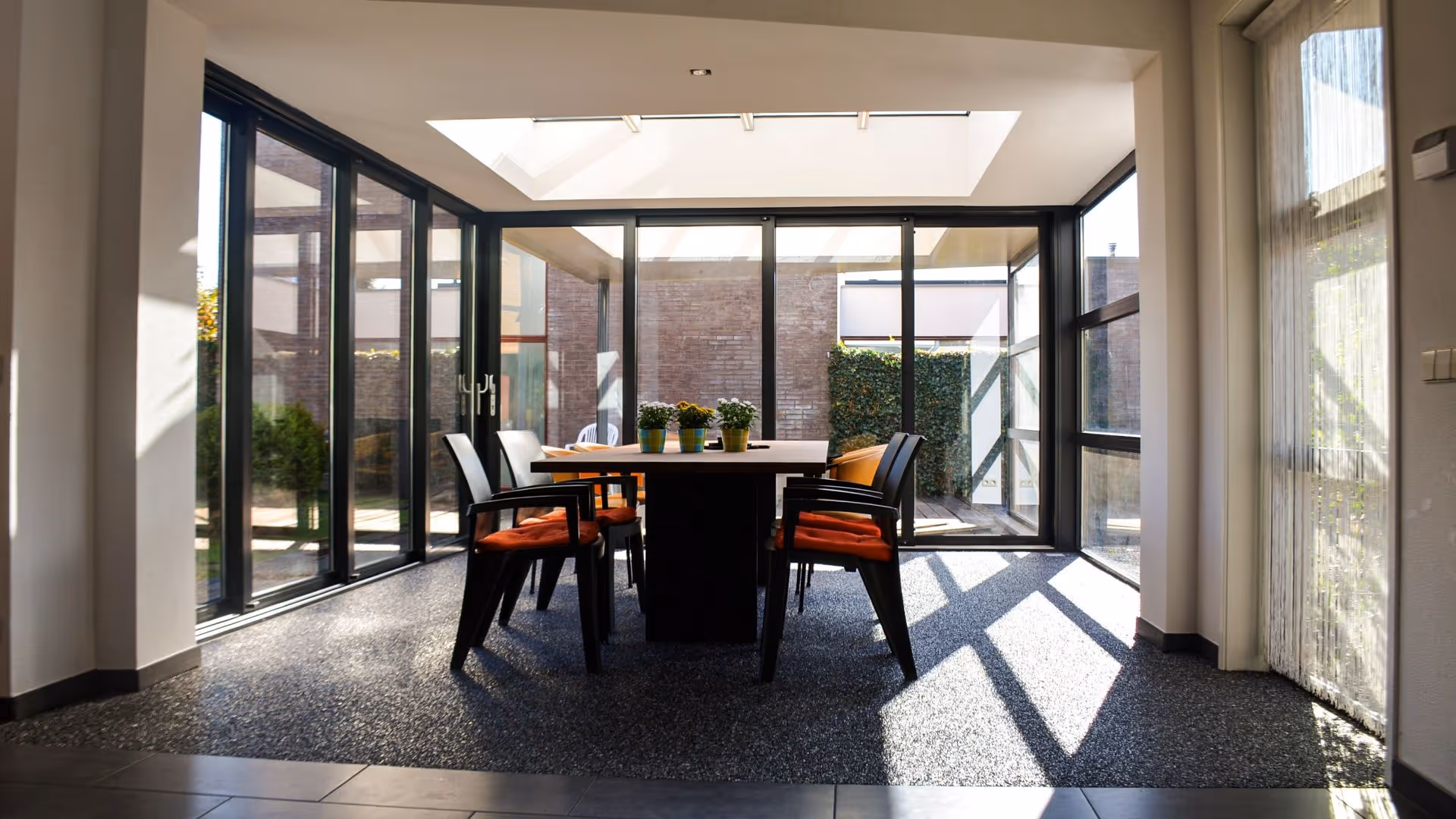 Exclusieve leefserre met glazen schuifwanden en royale lichtinval in moderne woning
