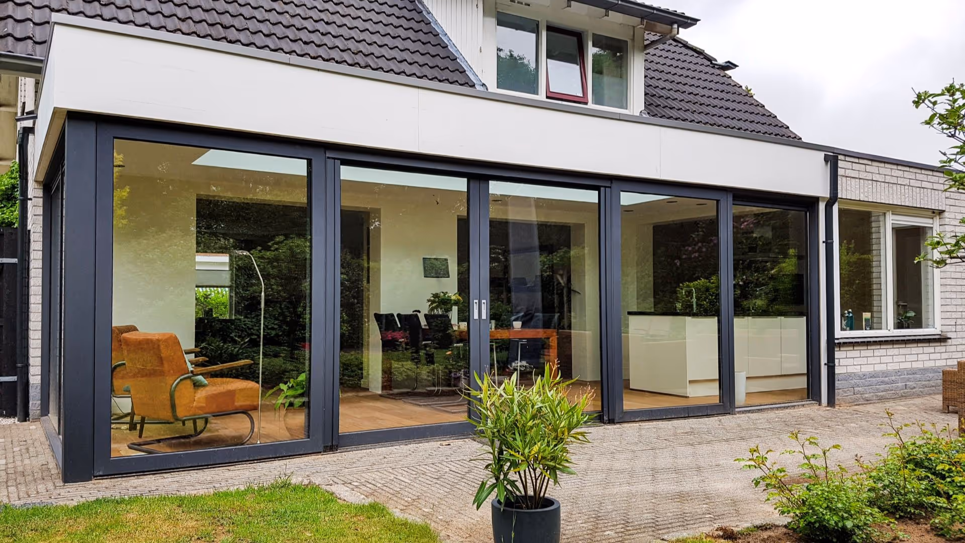 Strakke serre uitbreiding met veel glas en moderne woonkeuken vol daglicht