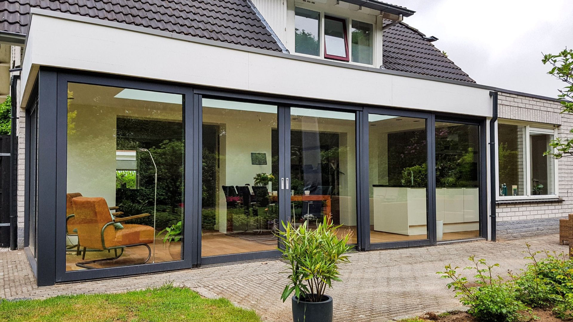 Strakke serre uitbreiding met veel glas en moderne woonkeuken vol daglicht