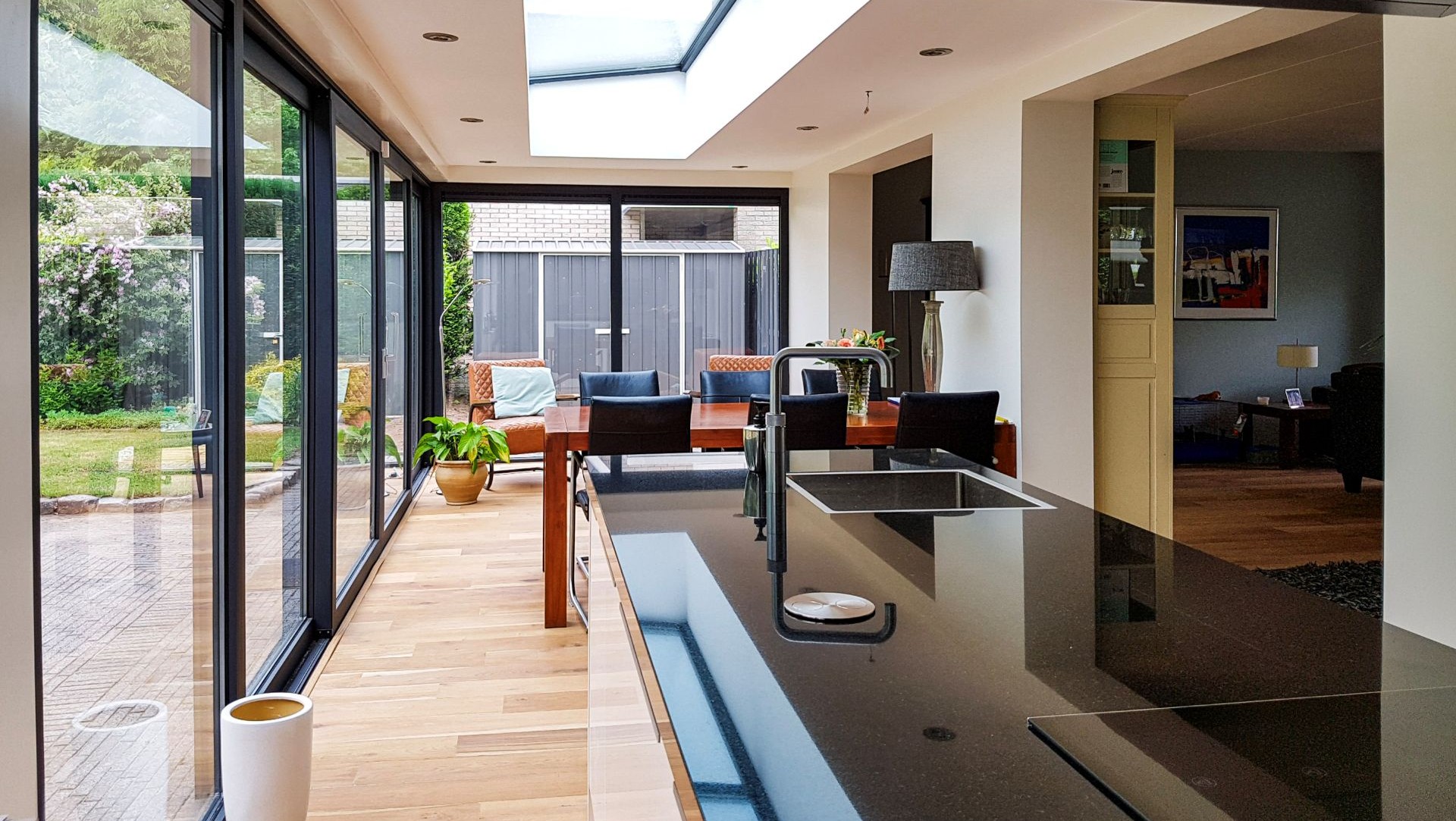 Luxe woonserre met glazen schuifwanden en moderne keuken met kookeiland