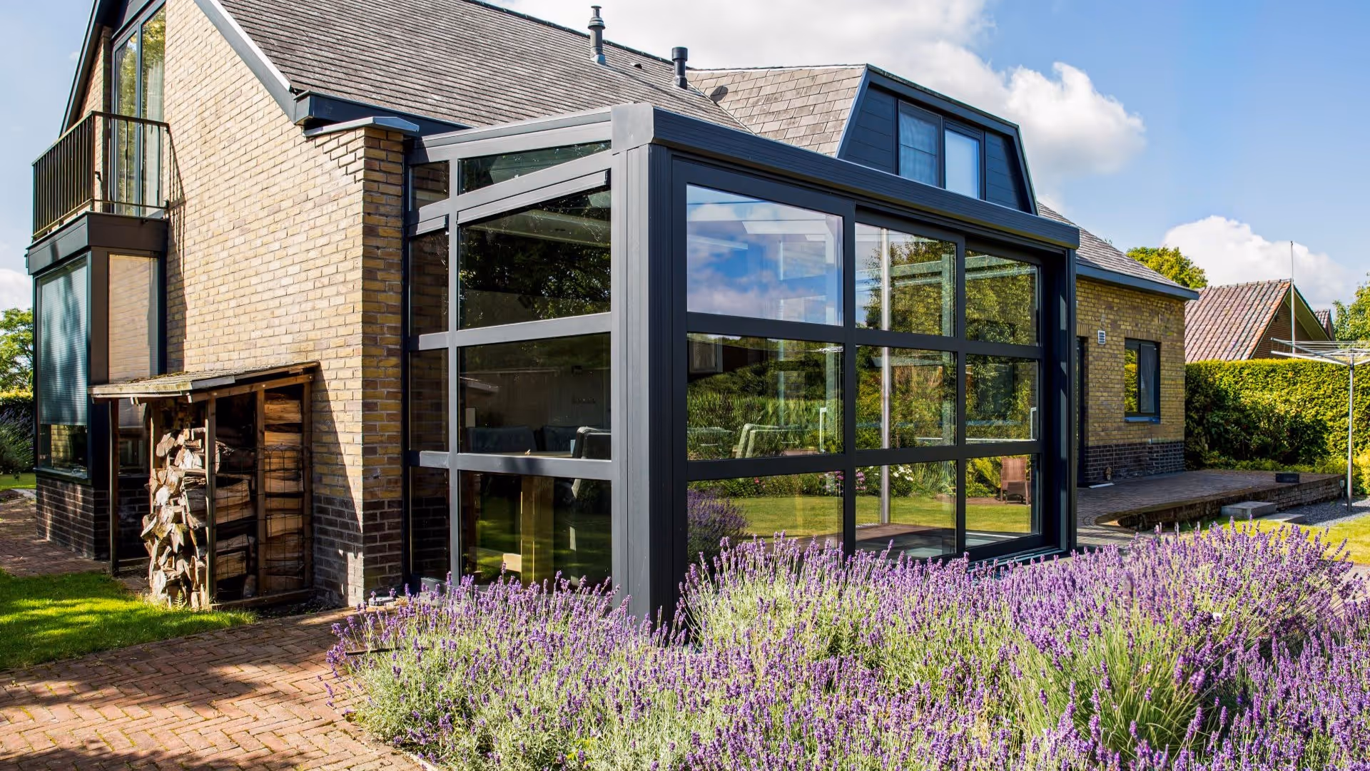 Luxe serre aanbouw met glazen dakconstructie en uitzicht op ruime achtertuin