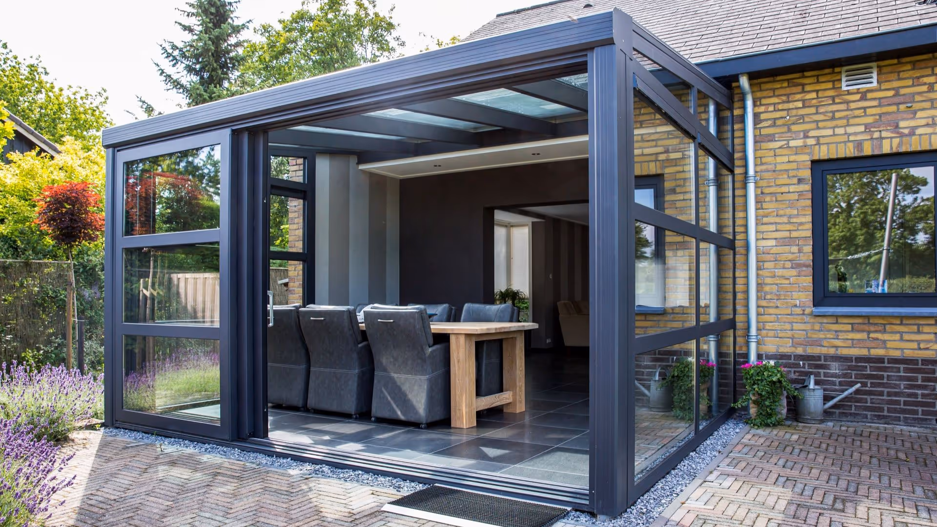 Moderne glazen serre aanbouw met zwarte aluminium kozijnen en ruime eetkamer
