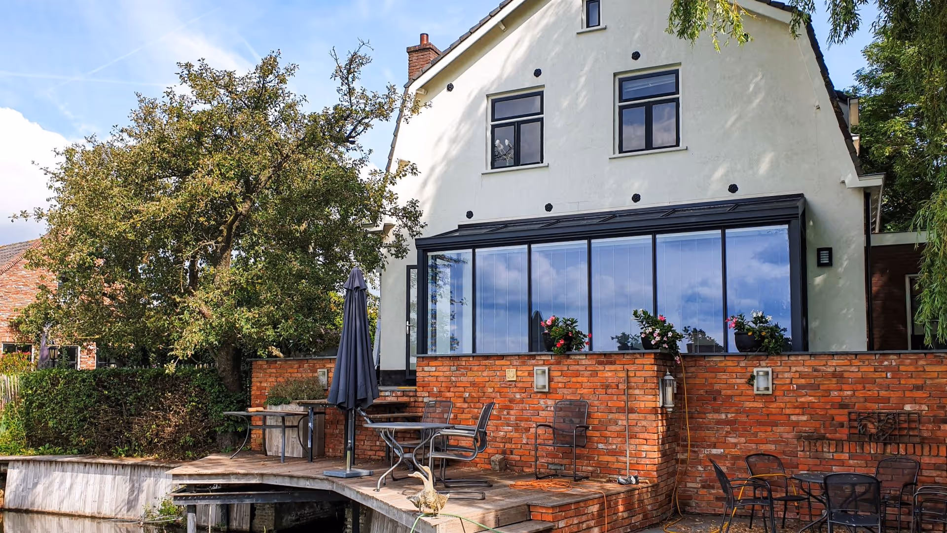 Luxe serre aanbouw met zwarte kozijnen en ruim terras aan het water