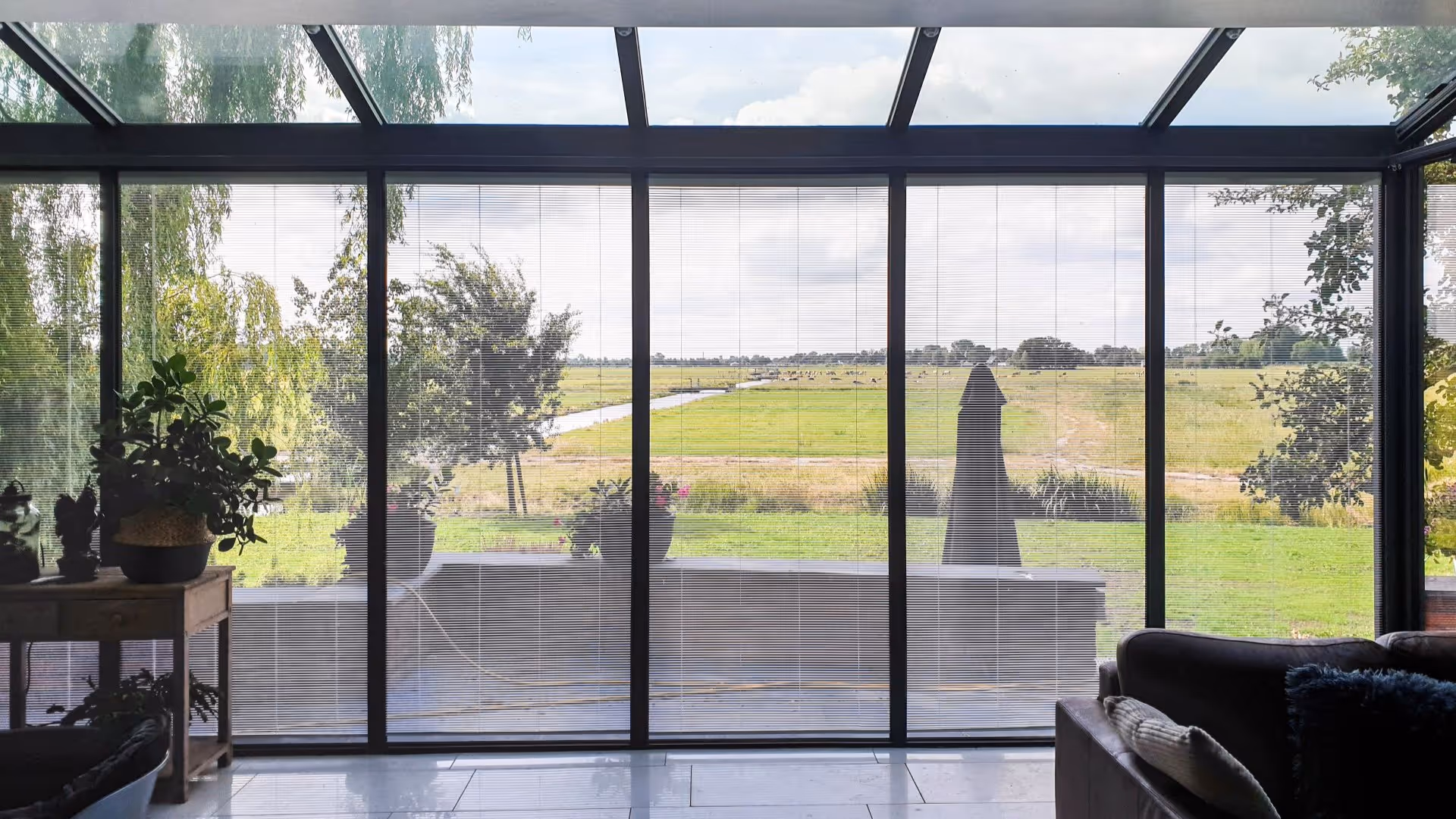 Moderne serre met glazen dak en grote raampartijen aan landelijke woning