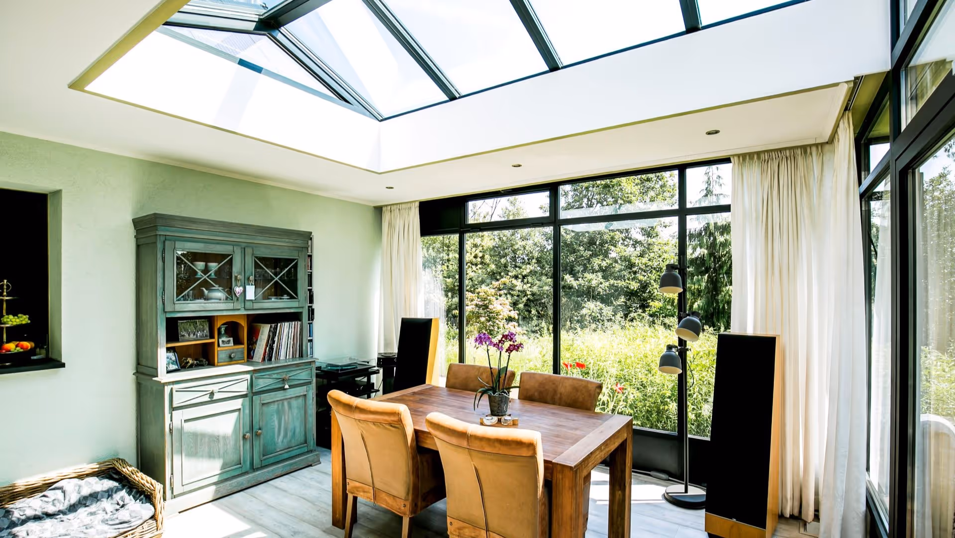 Luxe serre met glazen dak en stijlvolle eetkamer aan groene tuin
