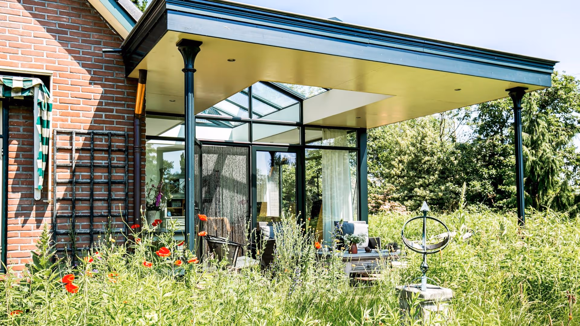 Luxe terrasoverkapping met glazen serre en uitzicht op weelderige tuin