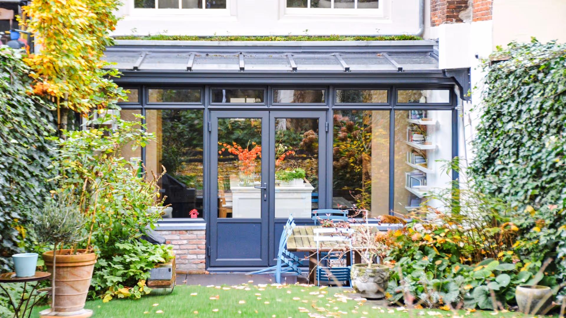 Moderne serre aanbouw met zwarte aluminium kozijnen en groene stadstuin