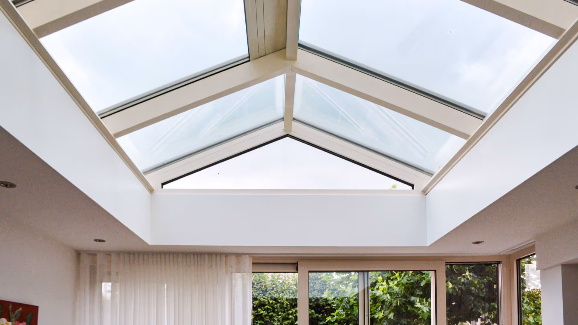 Moderne serre met wit glazen dak en veel natuurlijk licht in woonruimte