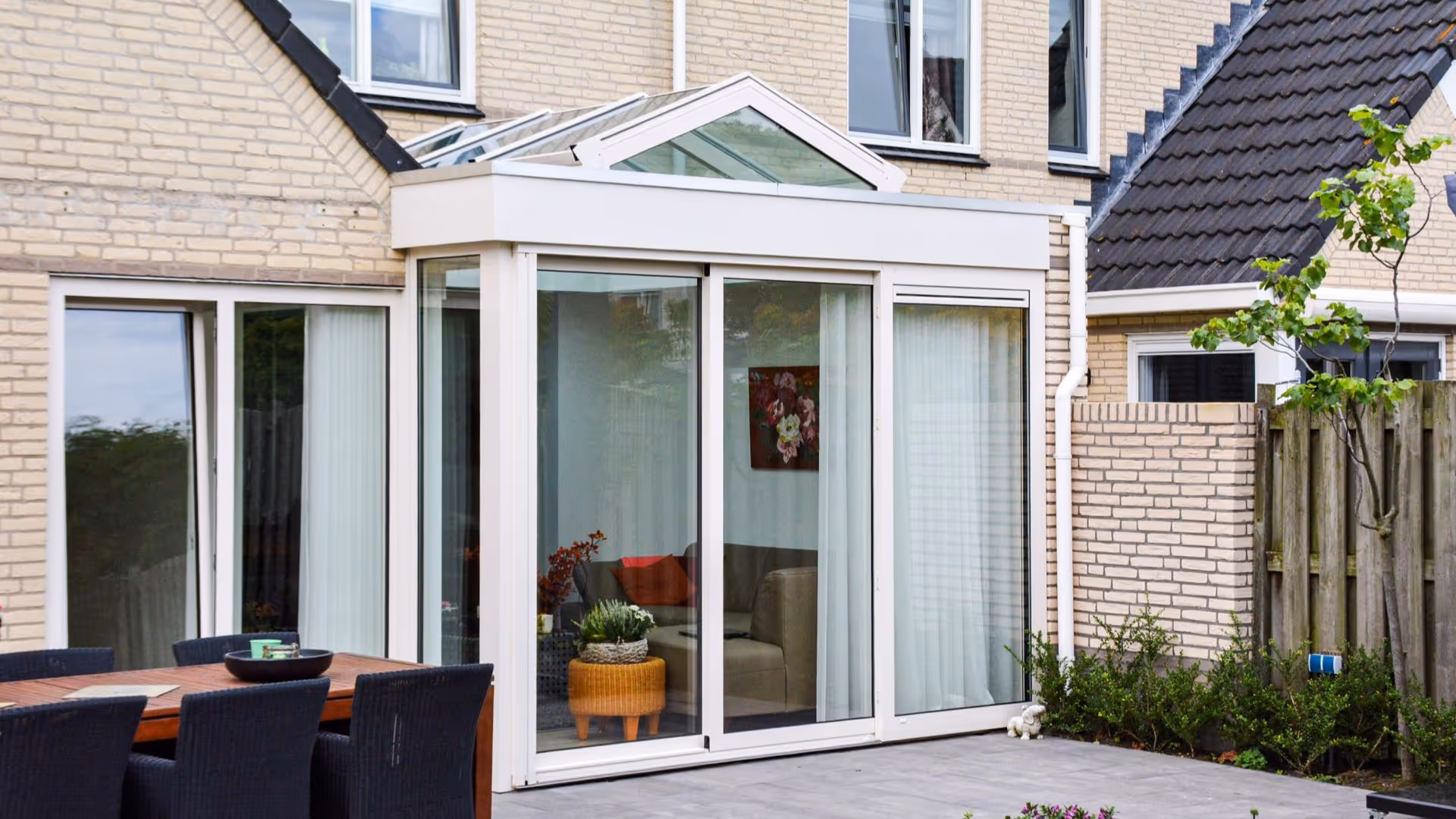 Moderne glazen serre aanbouw met lichtstraat en uitzicht op terras