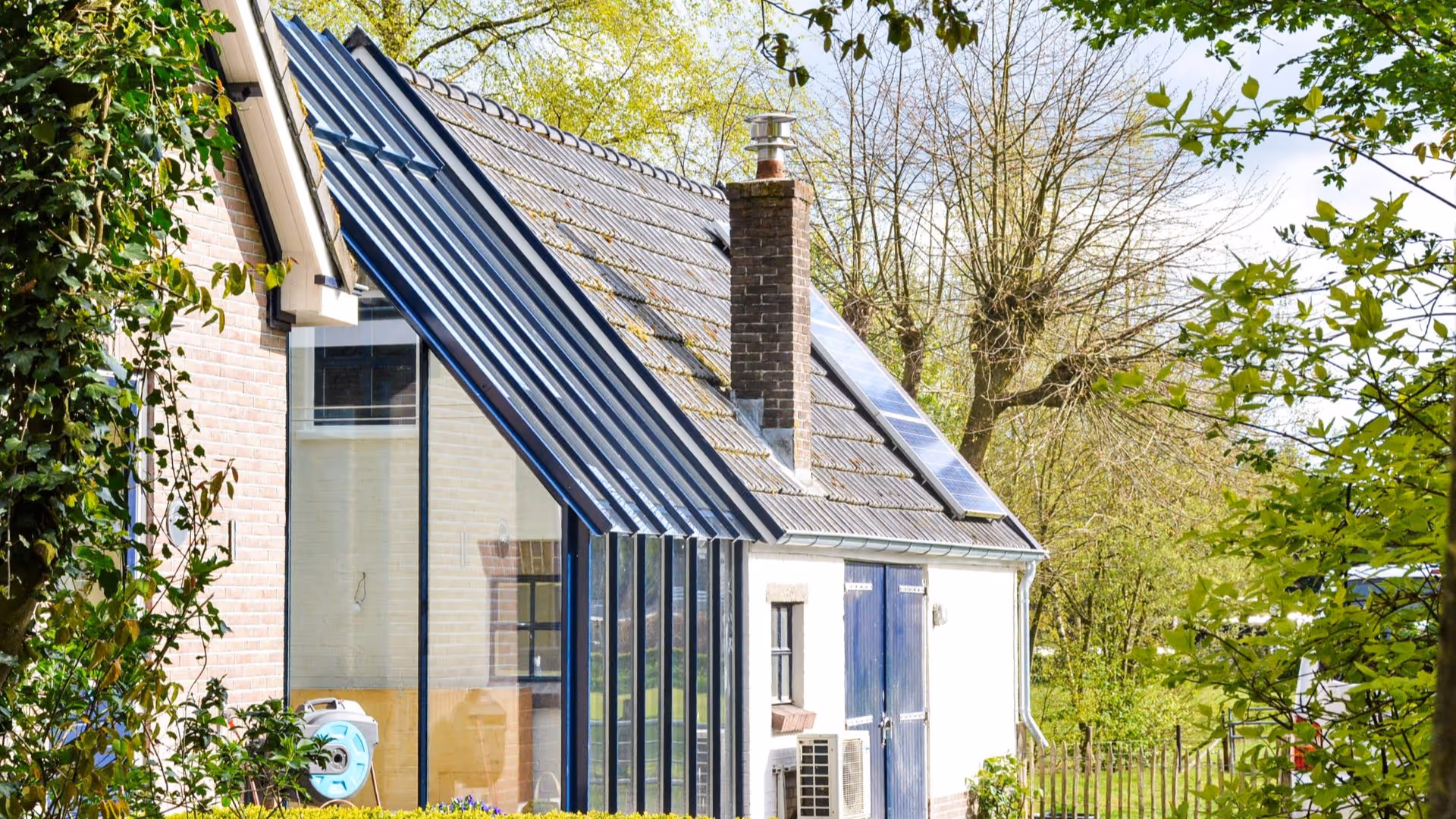Moderne glazen aanbouw met slank stalen frame en transparante dakpanelen