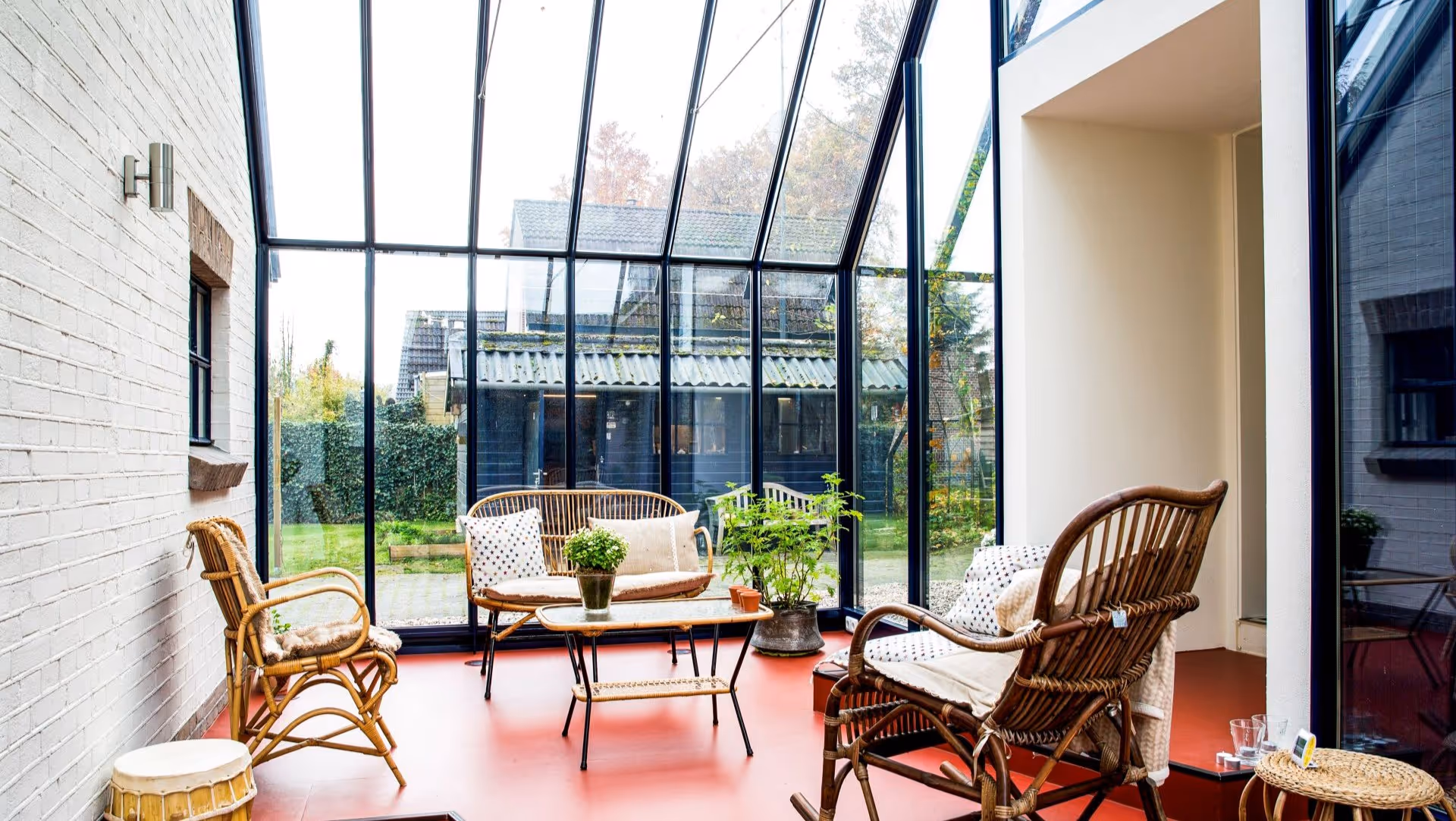 Lichte tuinkamer met glazen gevel en comfortabele zithoek met uitzicht op de tuin