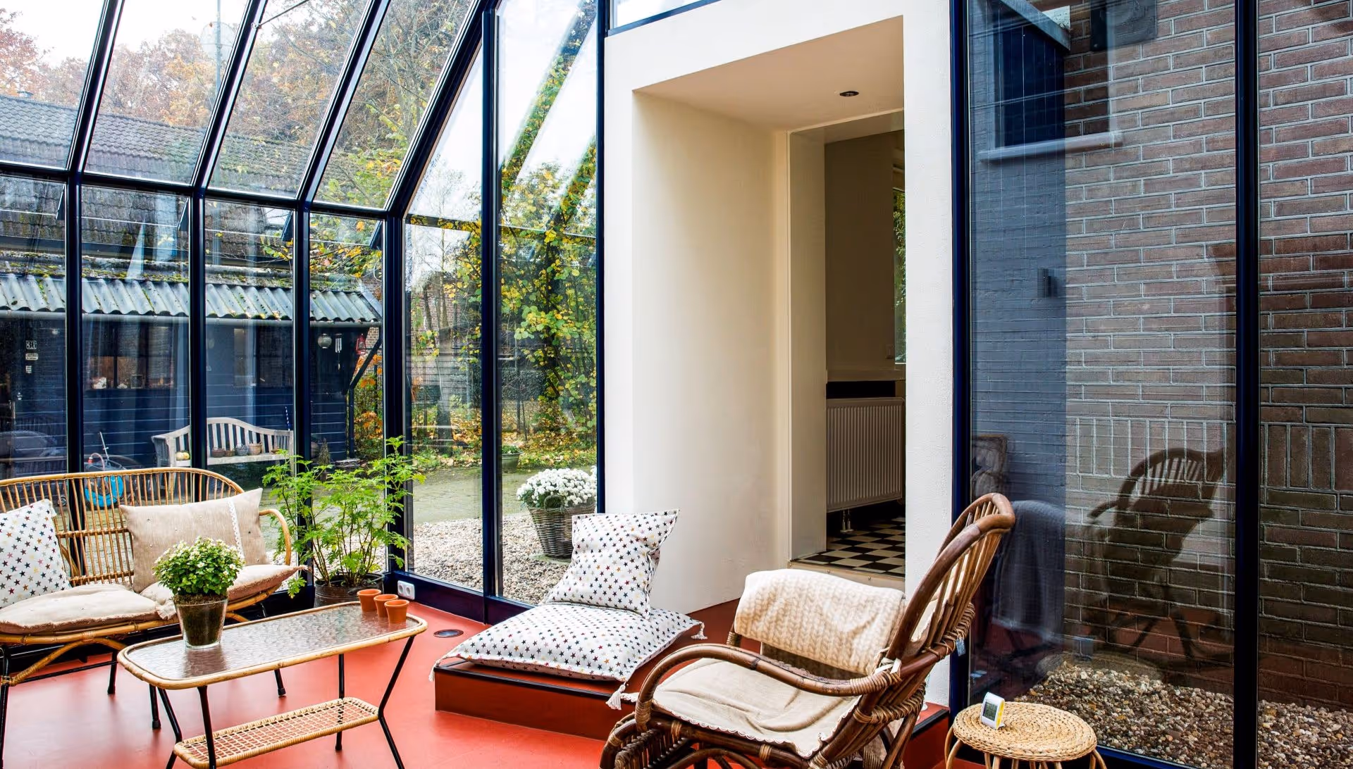 Interieur van lichte glazen woonuitbreiding met comfortabele zithoek en tuinzicht