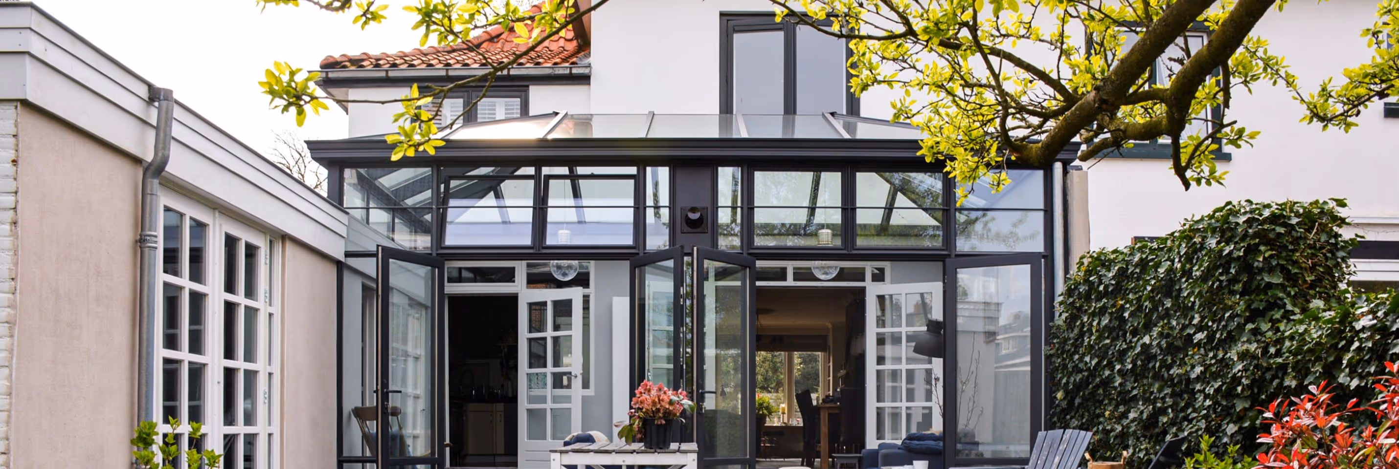 Steellook serre Heemstede - Luxe steellook serre met glazen dak en zwart aluminium kozijnen aan moderne woning.