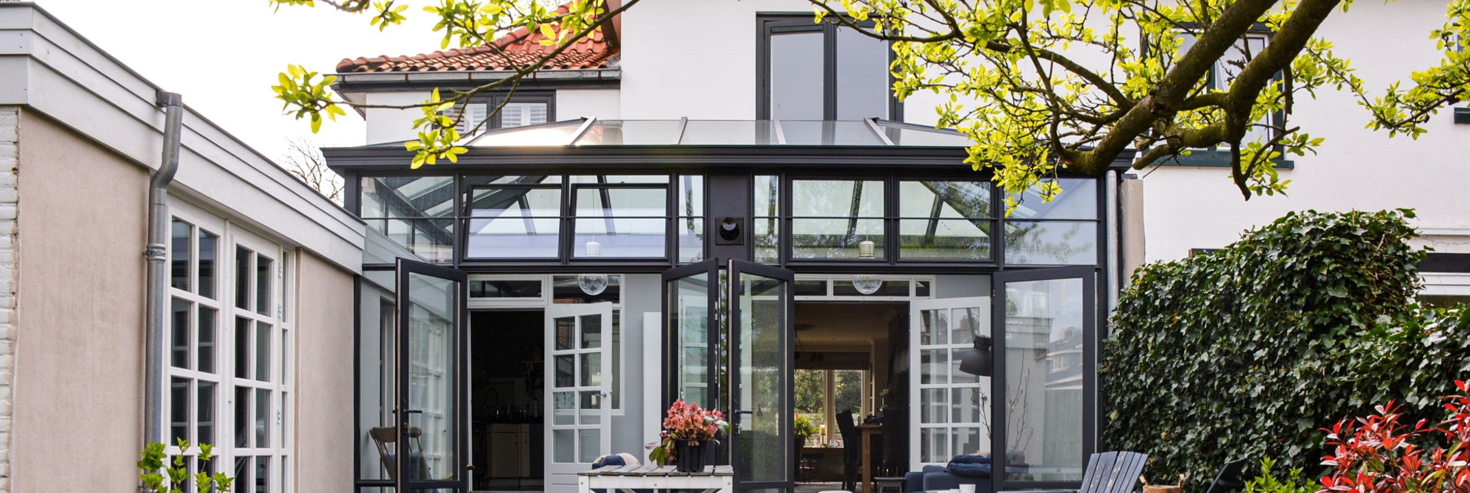 Steellook serre Heemstede - Luxe steellook serre met glazen dak en zwart aluminium kozijnen aan moderne woning.