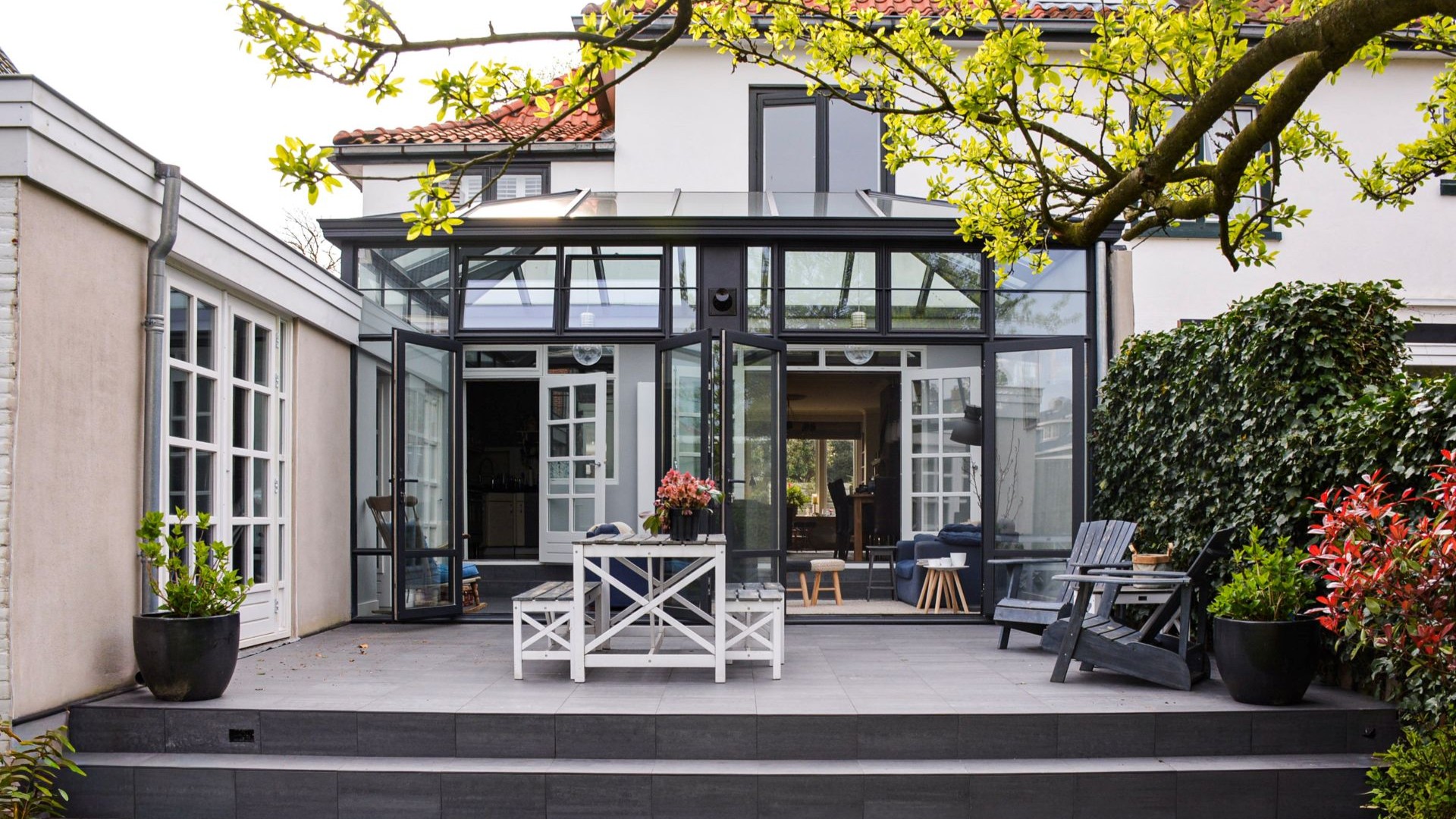 Ruime steellook tuinkamer met glazen wanden, zwart aluminium frame en strak terras.