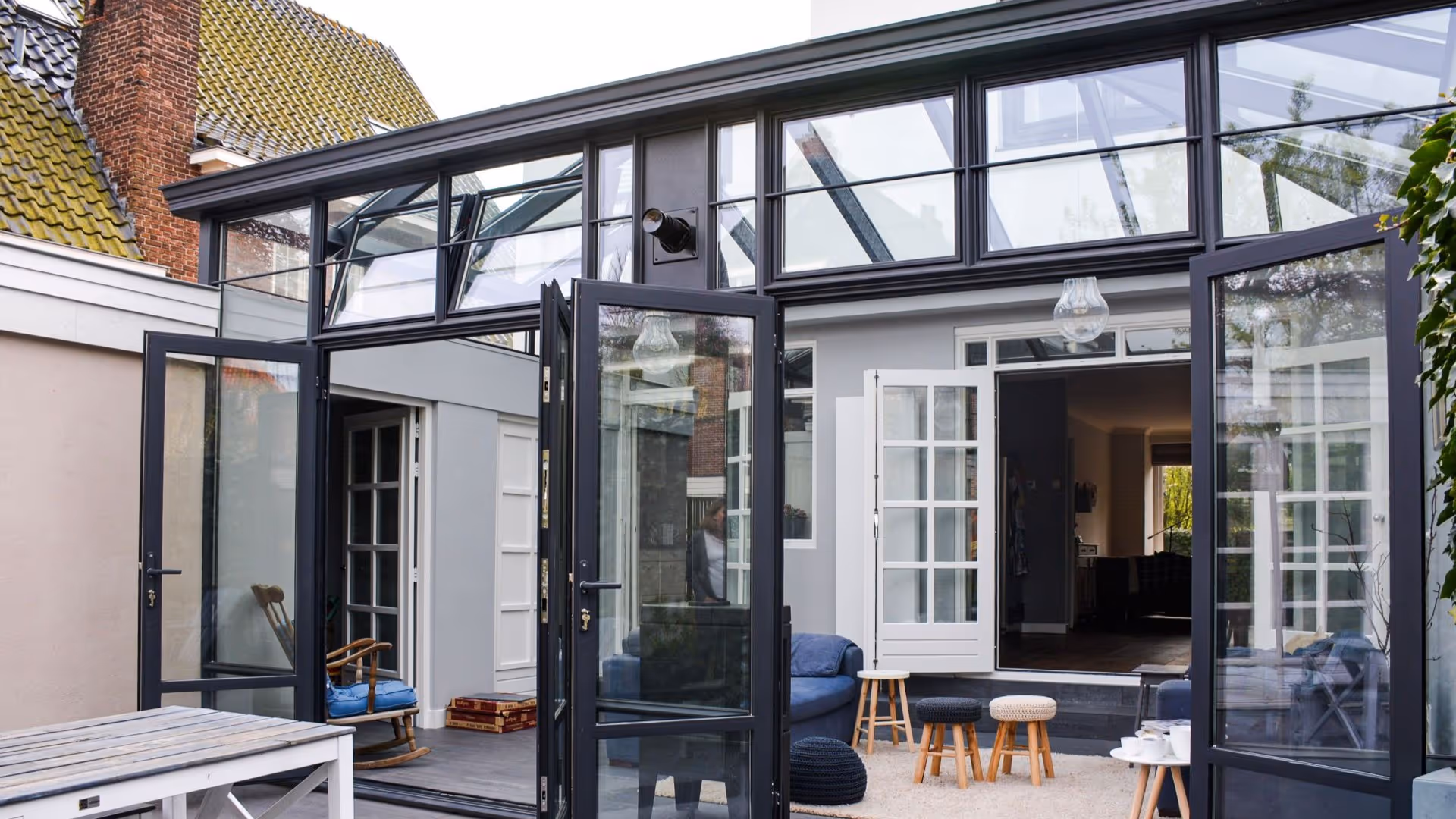 Moderne steellook serre met zwart aluminium frame, openslaande deuren en veel glas voor extra lichtinval.