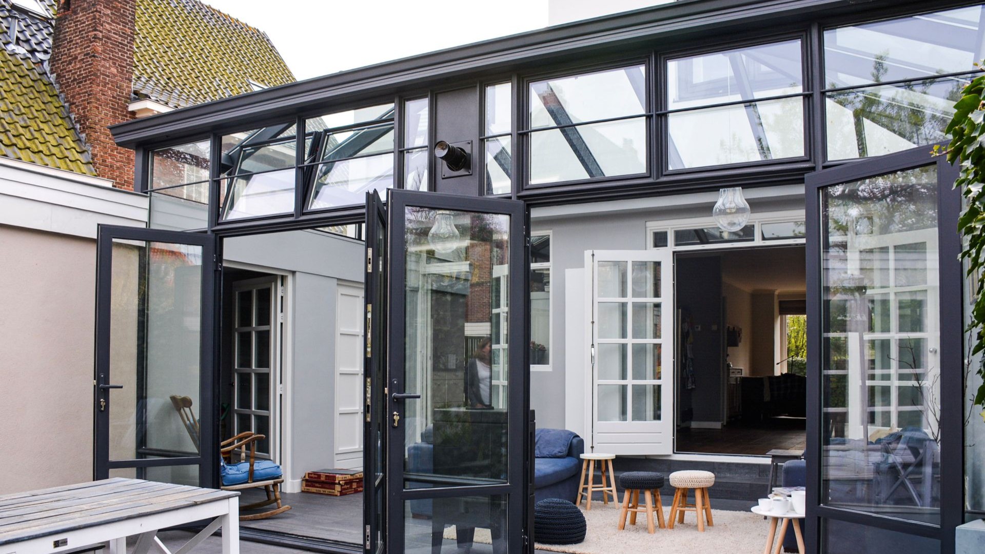 Moderne steellook serre met zwart aluminium frame, openslaande deuren en veel glas voor extra lichtinval.