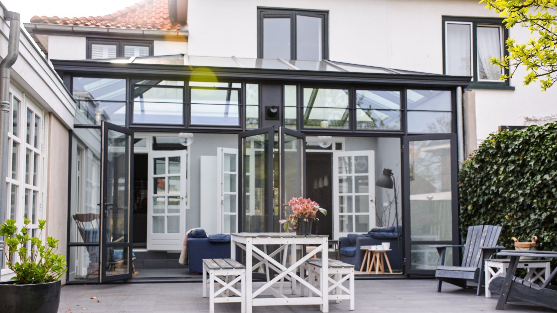 Moderne steellook woonuitbreiding met glazen dak en slanke zwarte aluminium profielen.