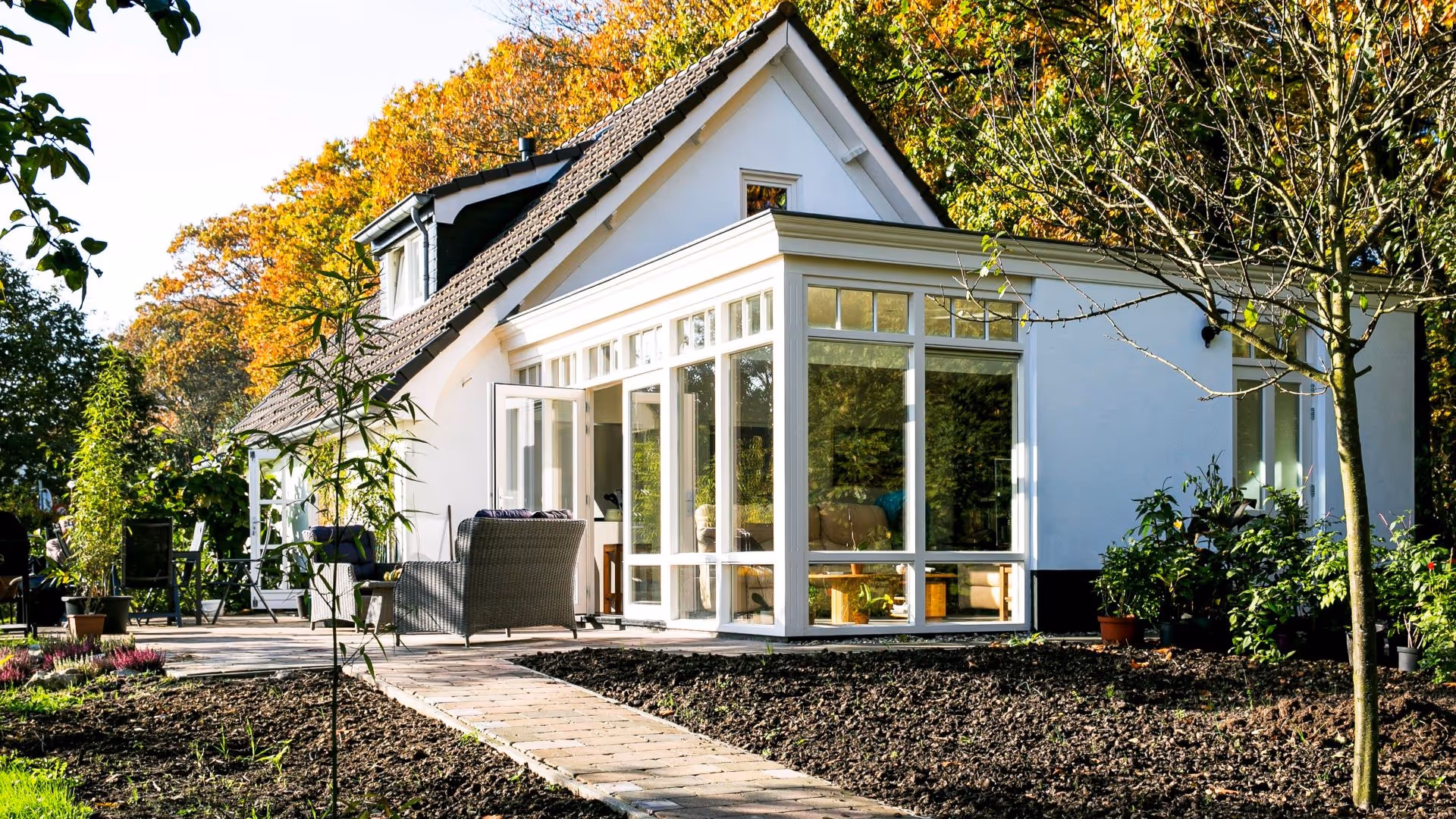 Klassieke witte serre met openslaande deuren, grote ramen en luxe uitstraling.