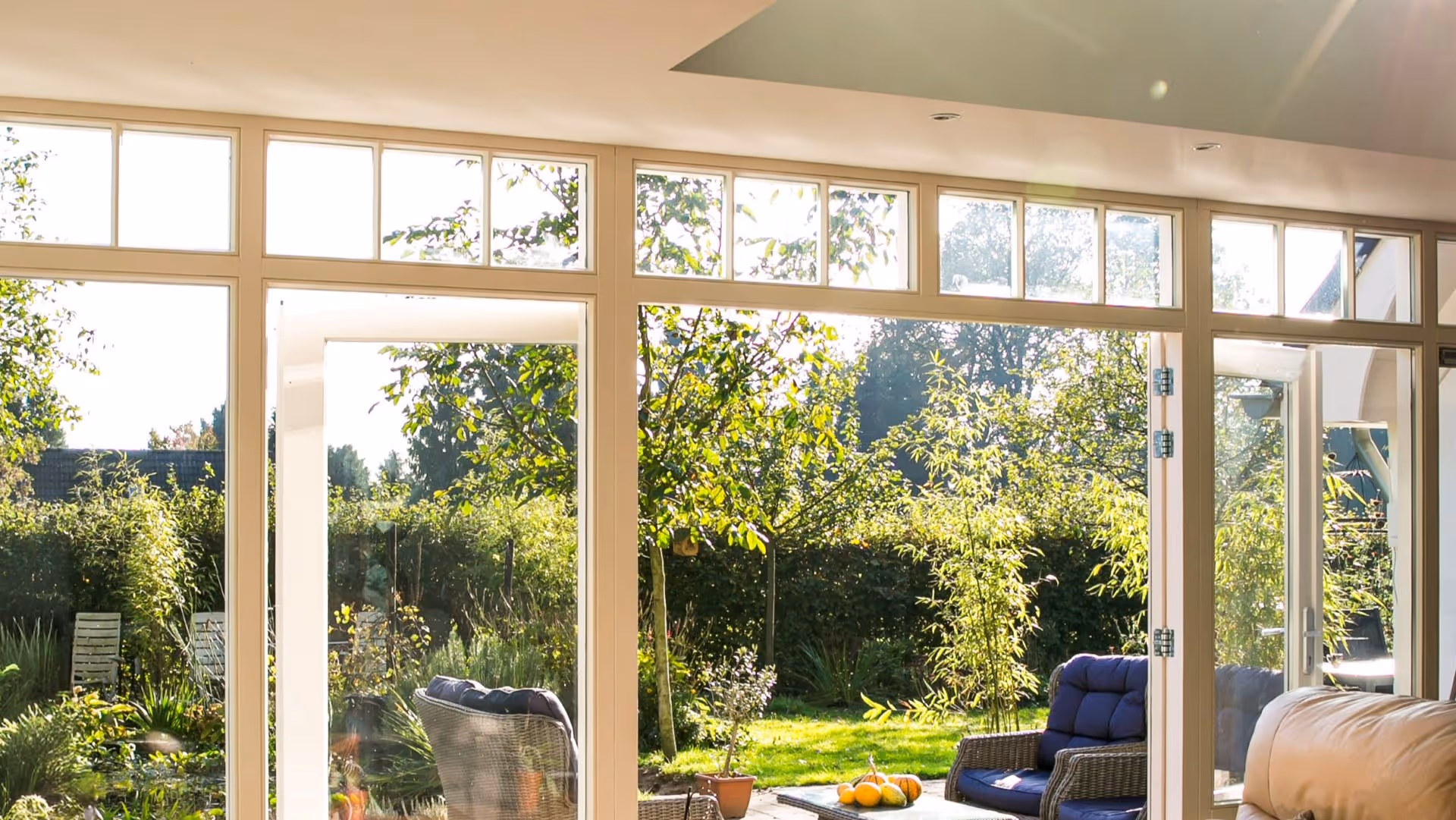 Uitzicht vanuit serre naar groene tuin met grote glaspuien en veel daglicht