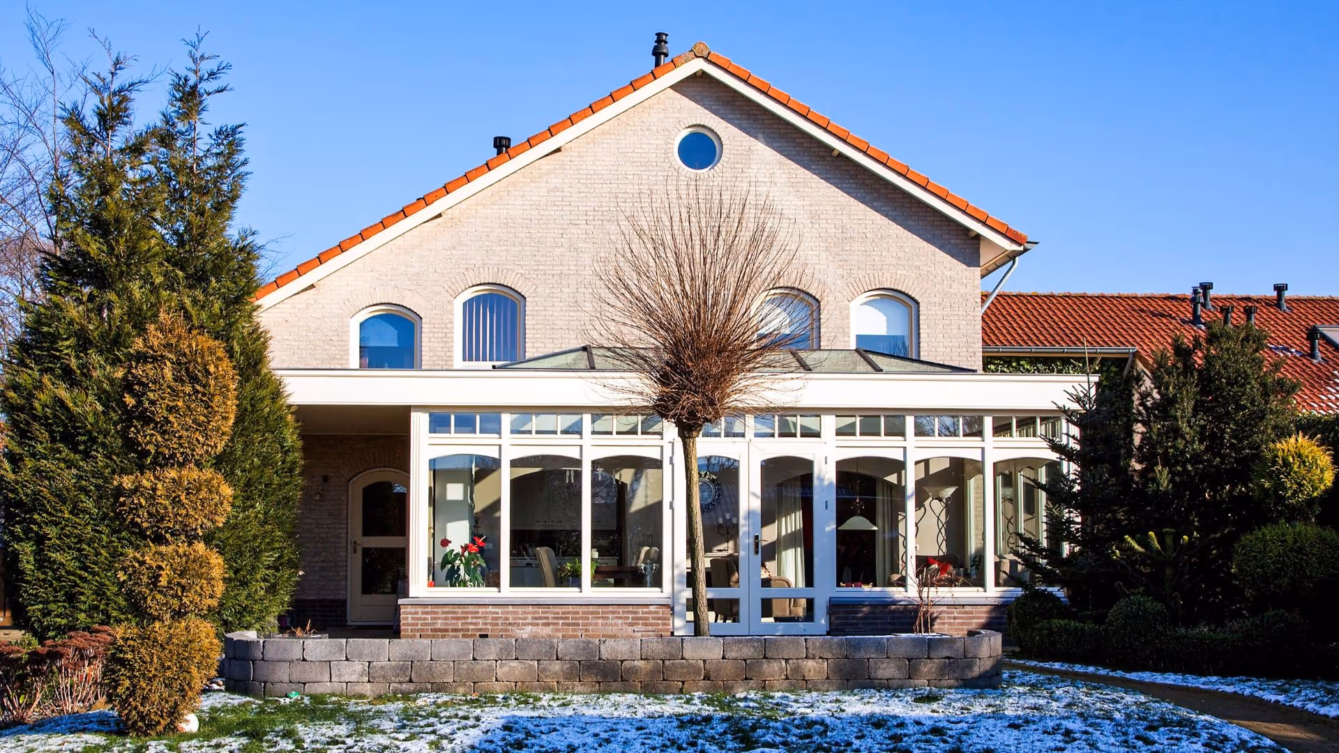 Ruime tuinkamer aan woning met glazen dakconstructie en veel natuurlijke lichtinval.