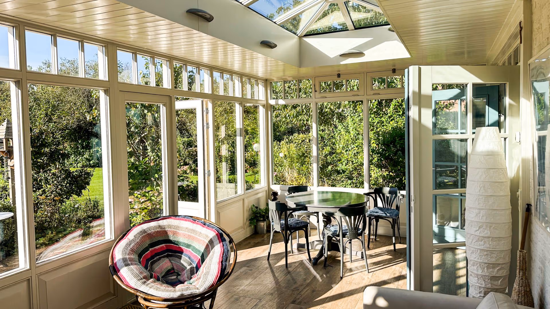 Lichte tuinkamer met glazen lichtstraat, grote ramen en uitzicht op een groene tuin.