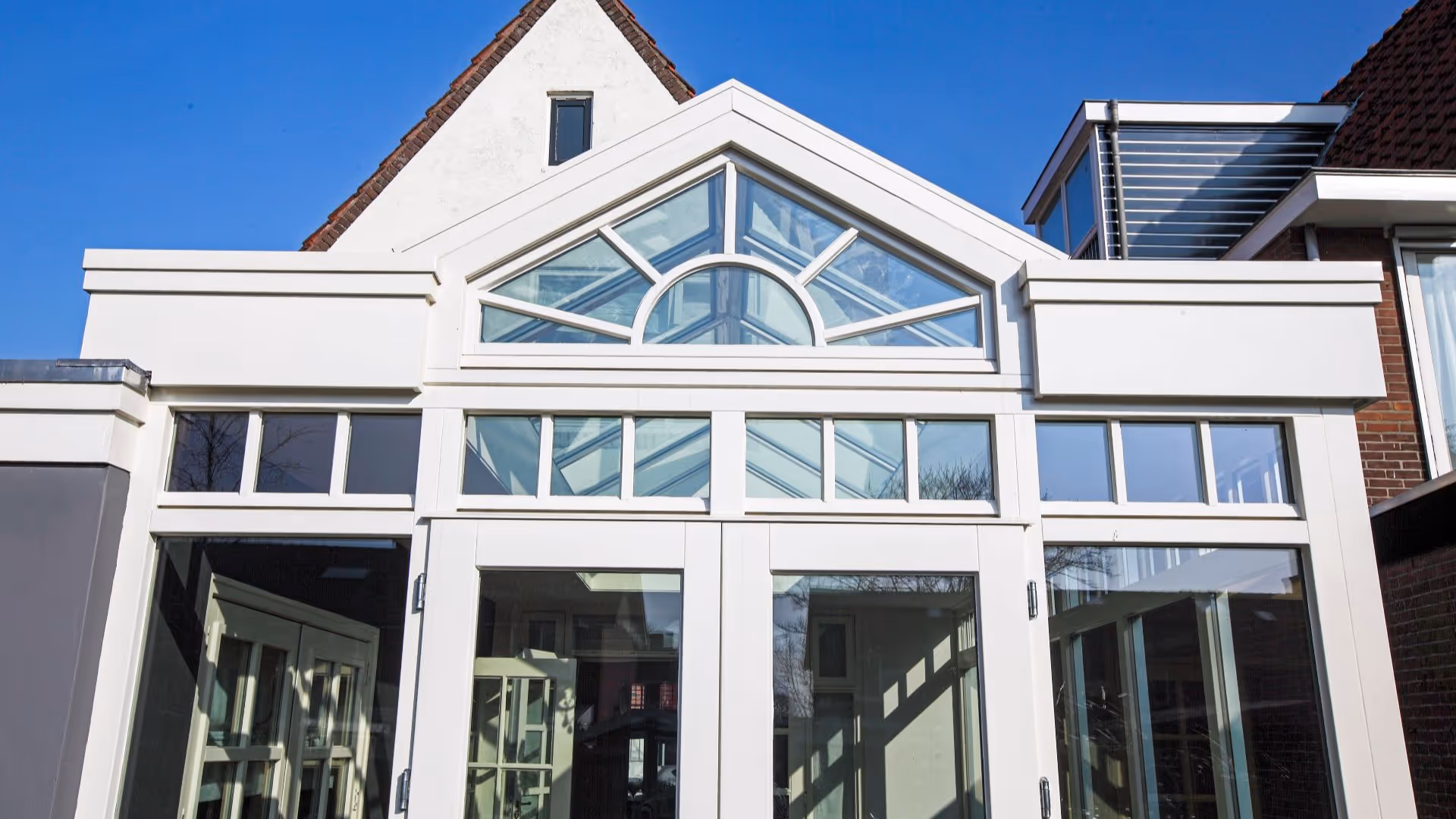 Terras met landelijke serre voorzien van hoge glaspartijen en een opvallende glazen topgevel.
