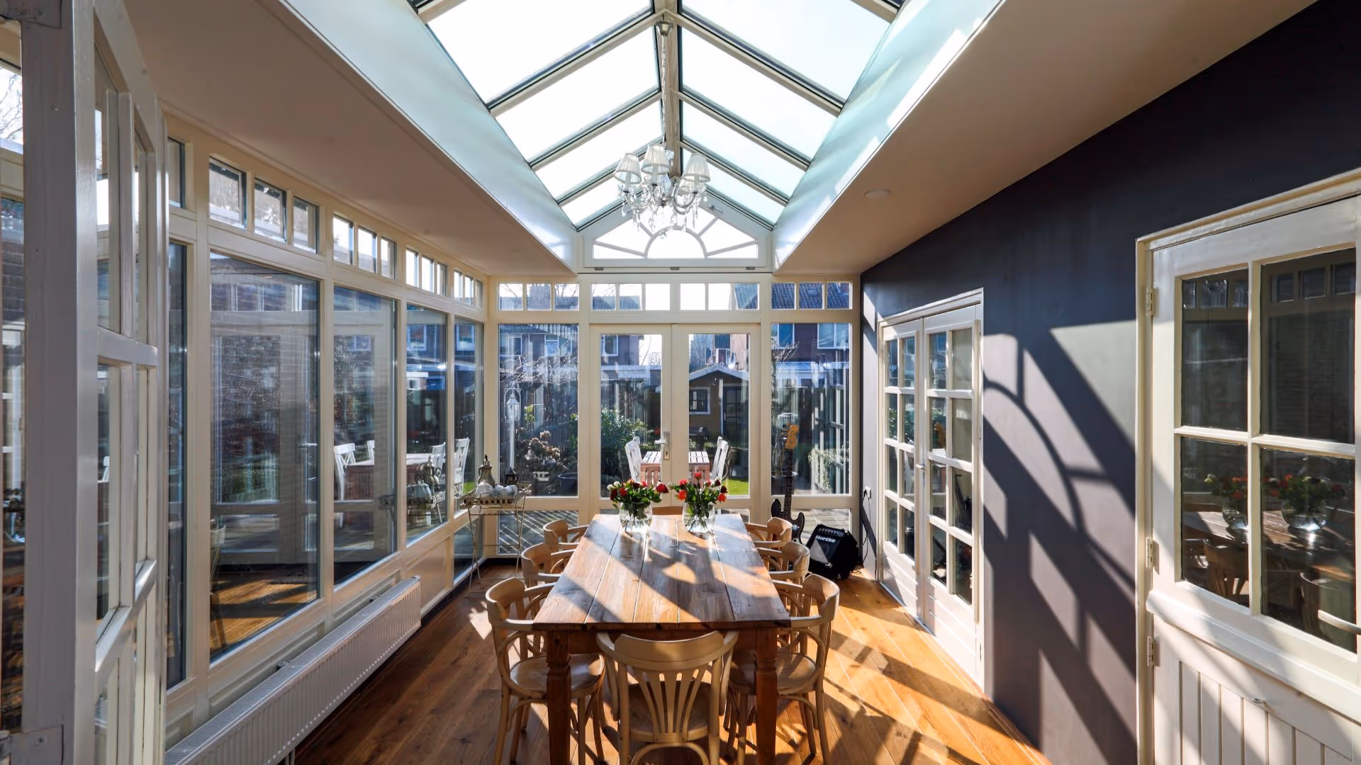 Lichte tuinkamer met glazen lichtstraat, royale eettafel en uitzicht op de tuin.