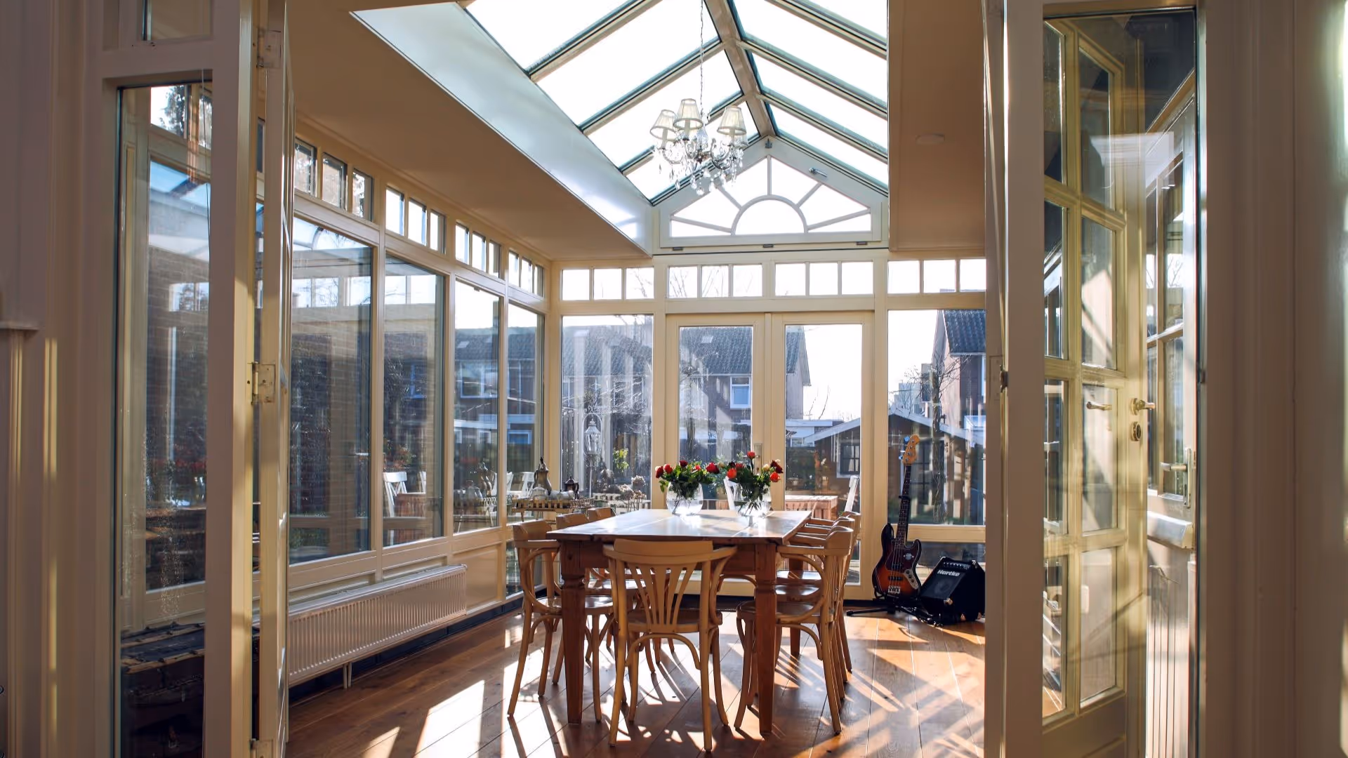 Landelijke serre met lichtstraat, grote glasoppervlakken en comfortabele eetkamer aan huis.