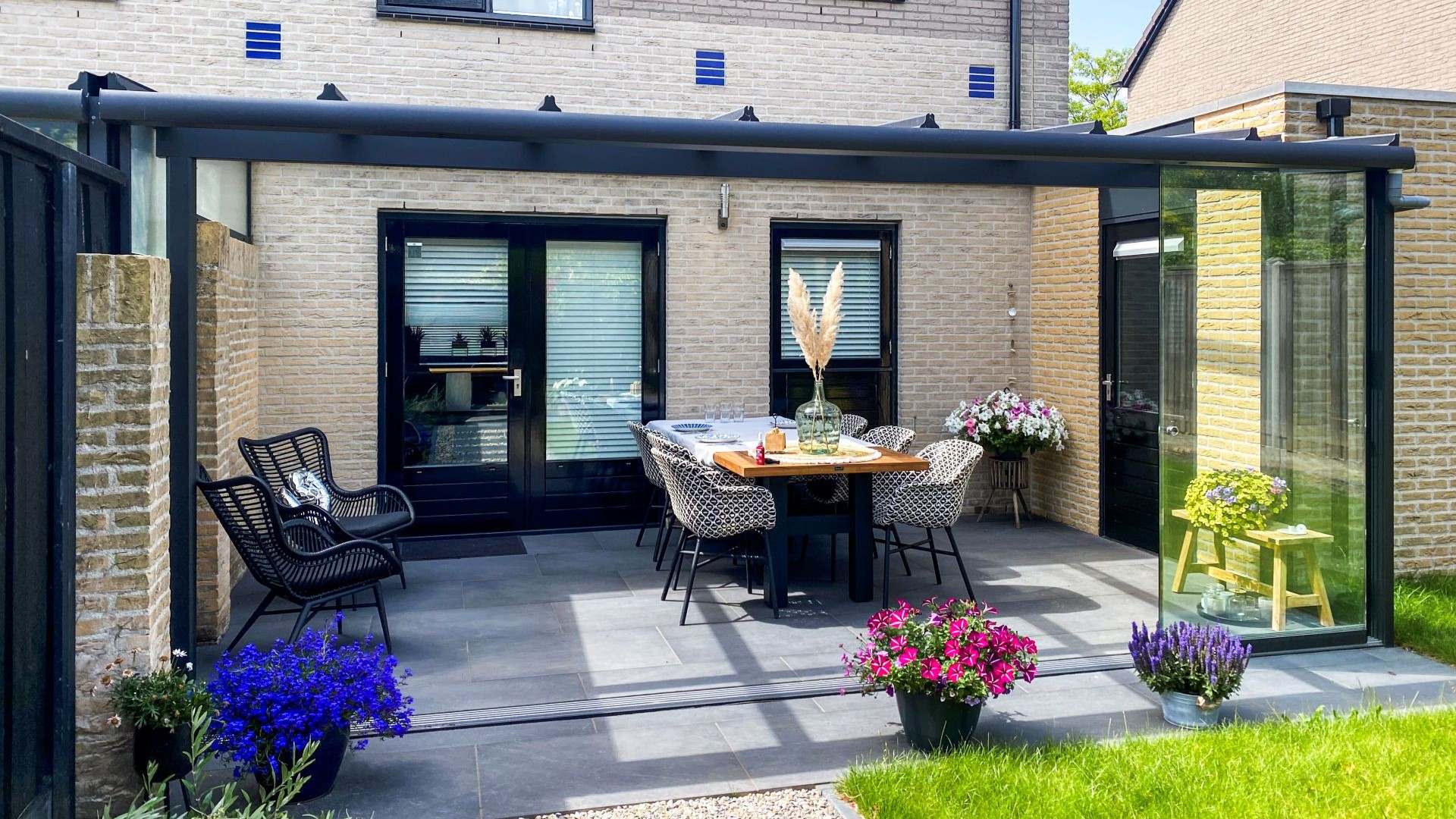 Moderne aluminium terrasoverkapping met glazen schuifwand en stijlvolle buitenruimte