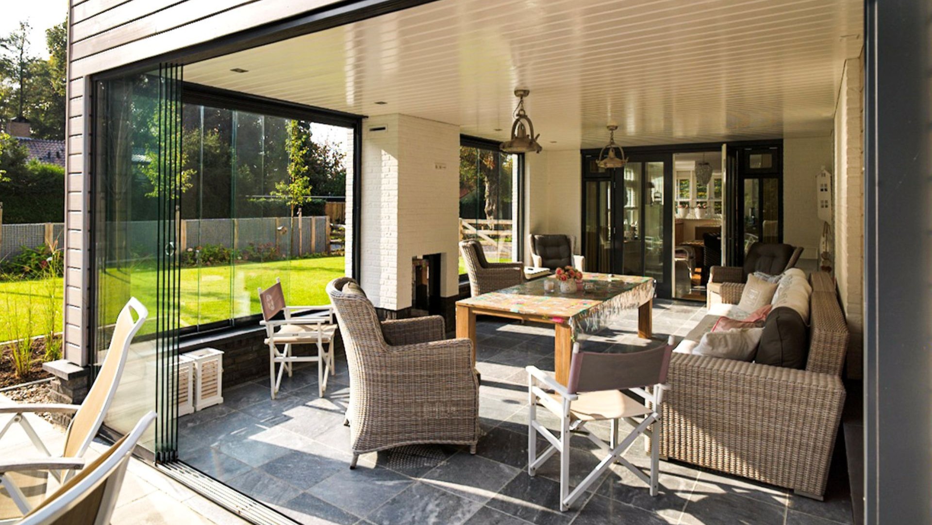 Sfeervolle tuinkamer met glazen schuifwanden, open haard en uitzicht op de tuin