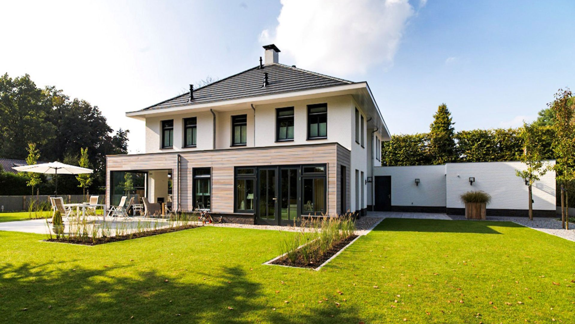 Uitzicht vanuit een luxe tuinkamer naar zonnig terras en strak aangelegde tuin