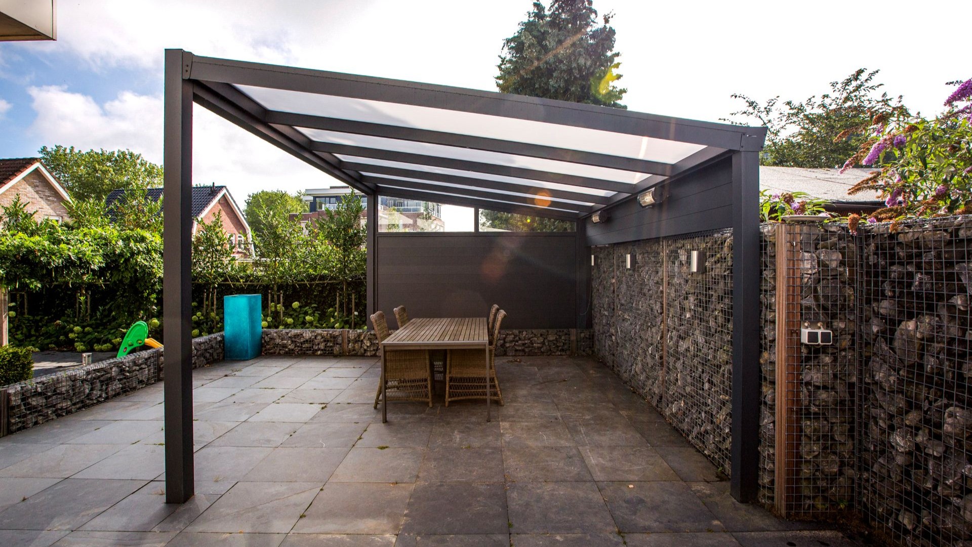 Moderne veranda met donkere aluminium constructie, verlichting en stijlvolle schanskorfwand
