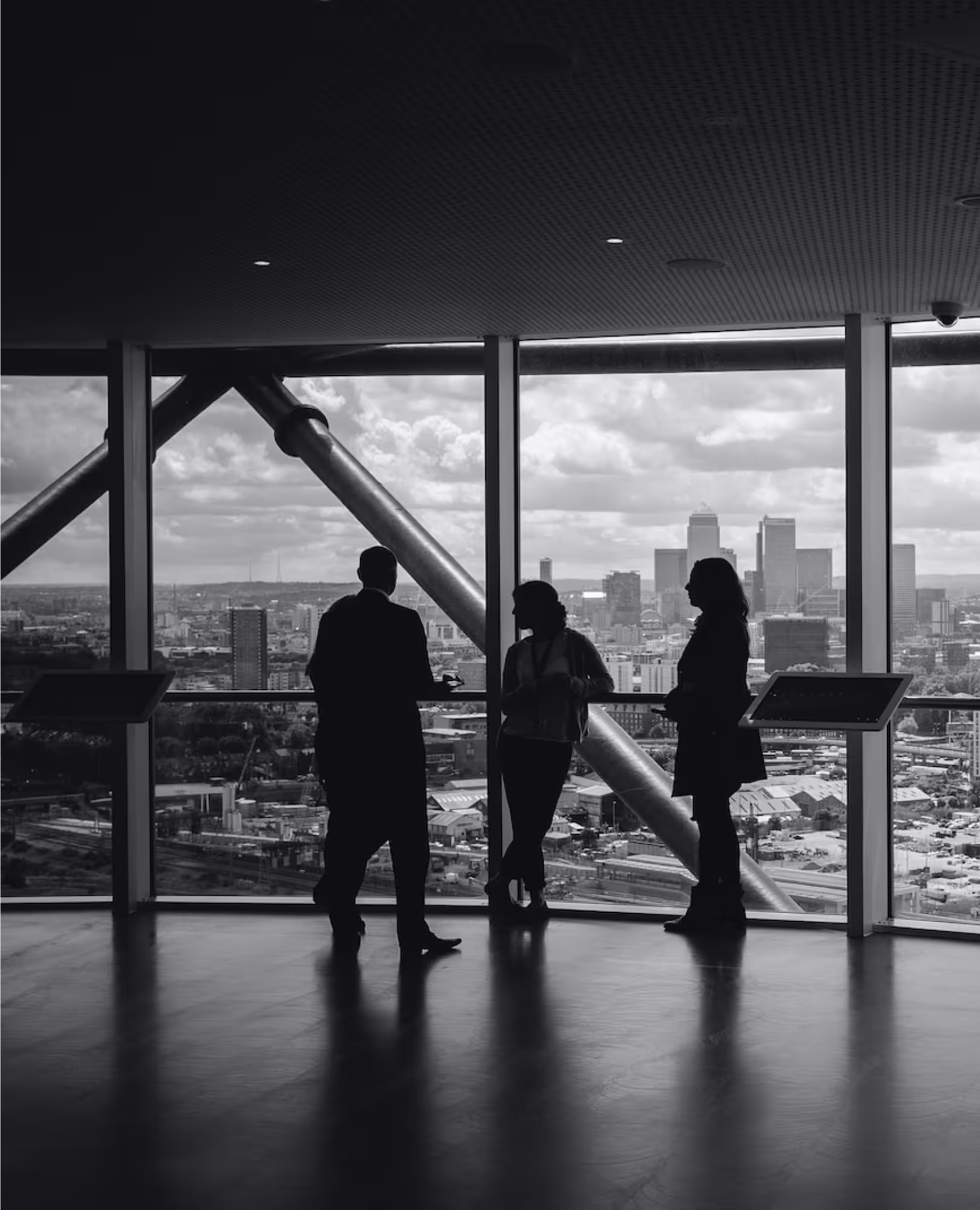 B2B Bild. Drei Menschen stehen for einer großen Fensterfront.