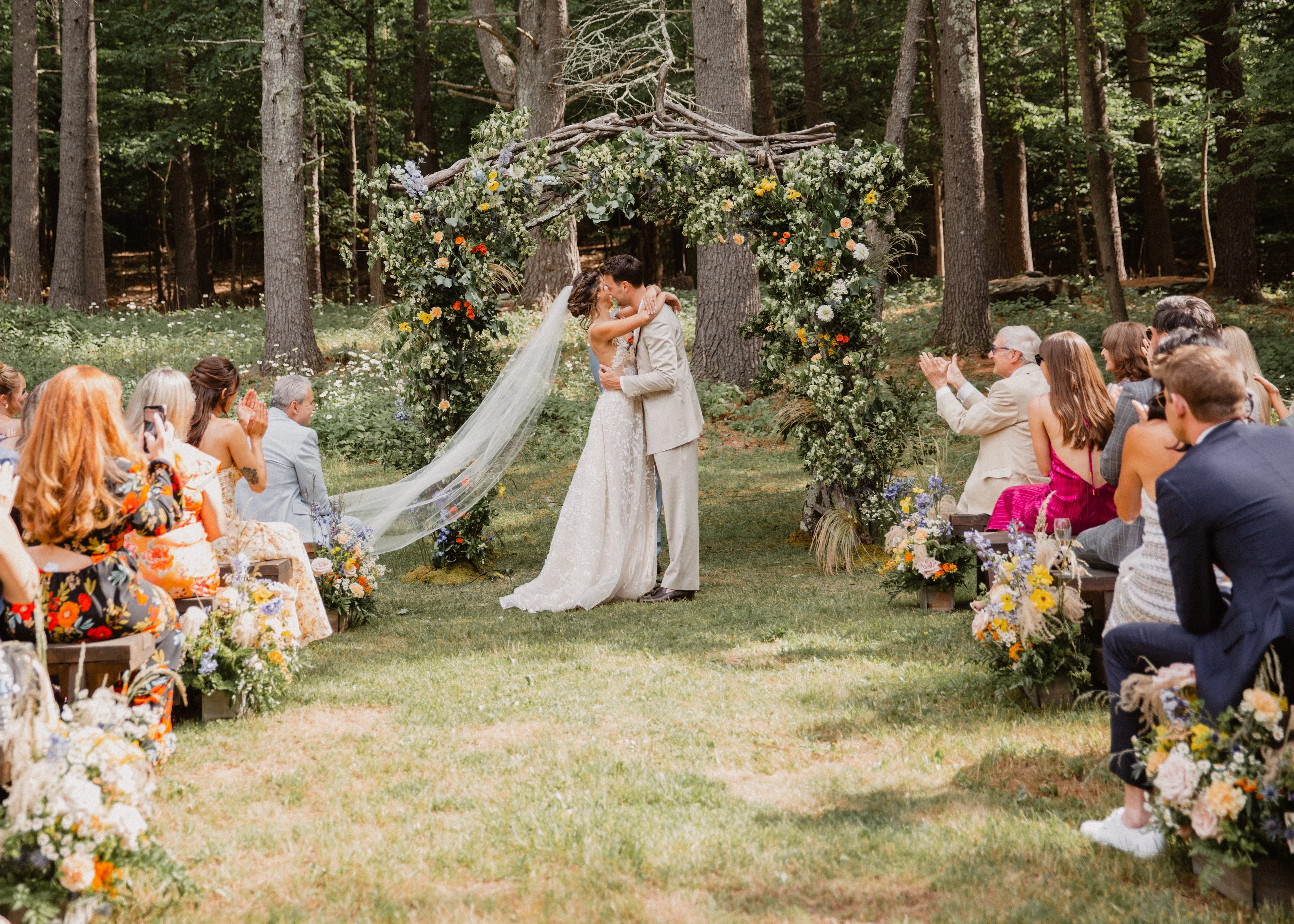 Woodland wedding ceremony under a branch and wildflower arch at Glen Falls House