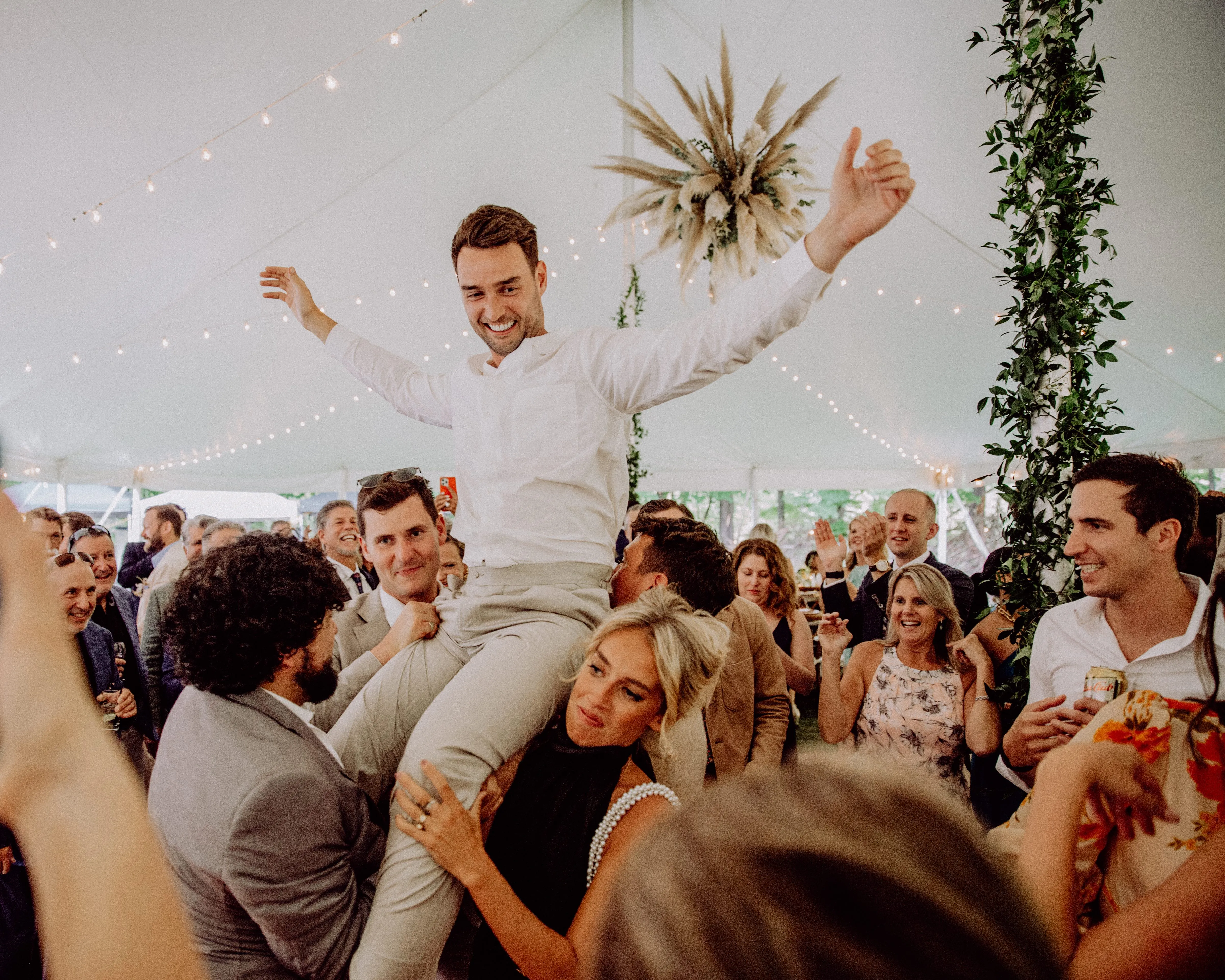 Guests celebrating on the dance floor beneath a hanging pampas grass installation at Glen Falls House