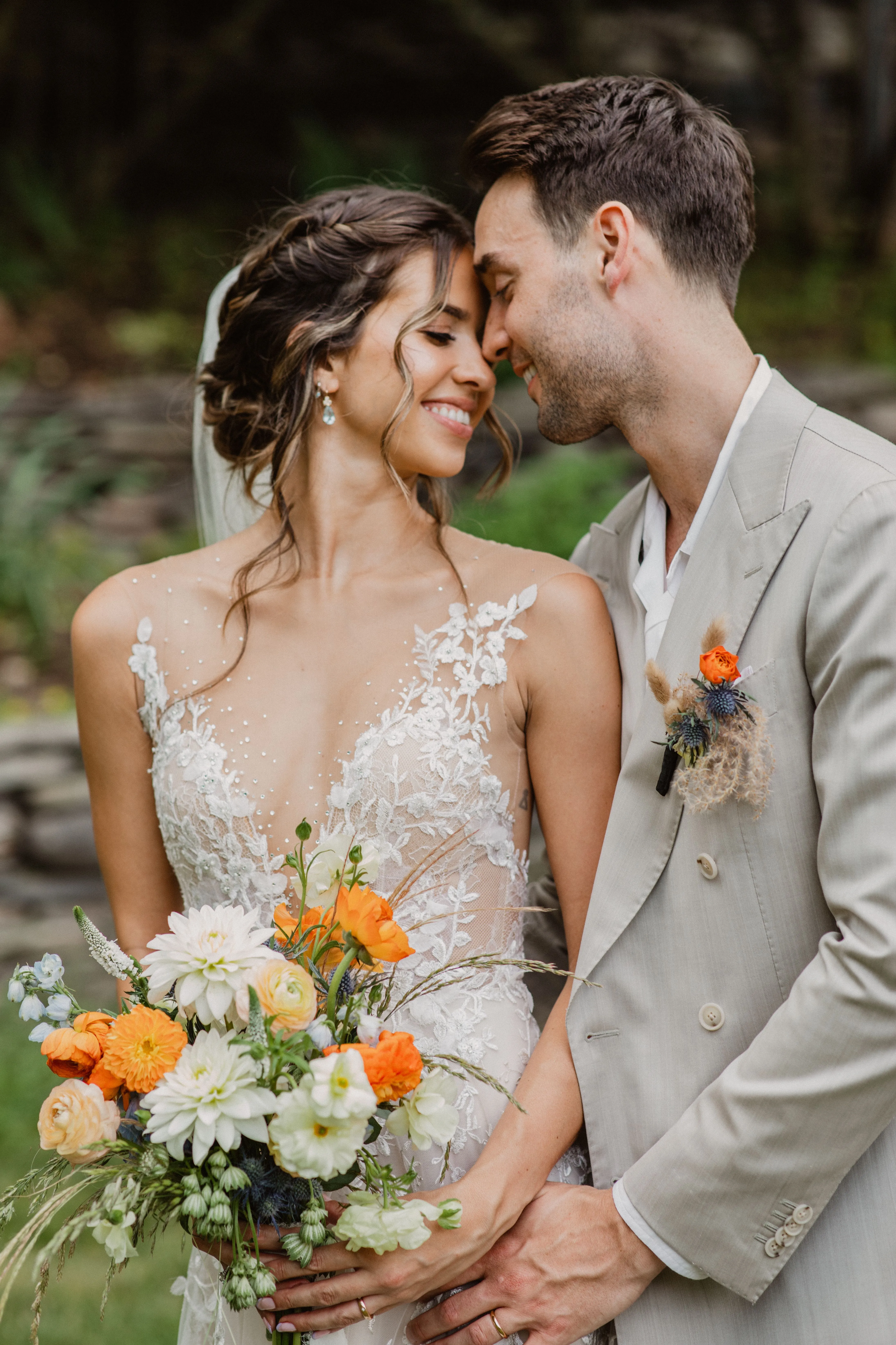 Bride and groom with a colorful wildflower bridal bouquet and boutonniere at Glen Falls House