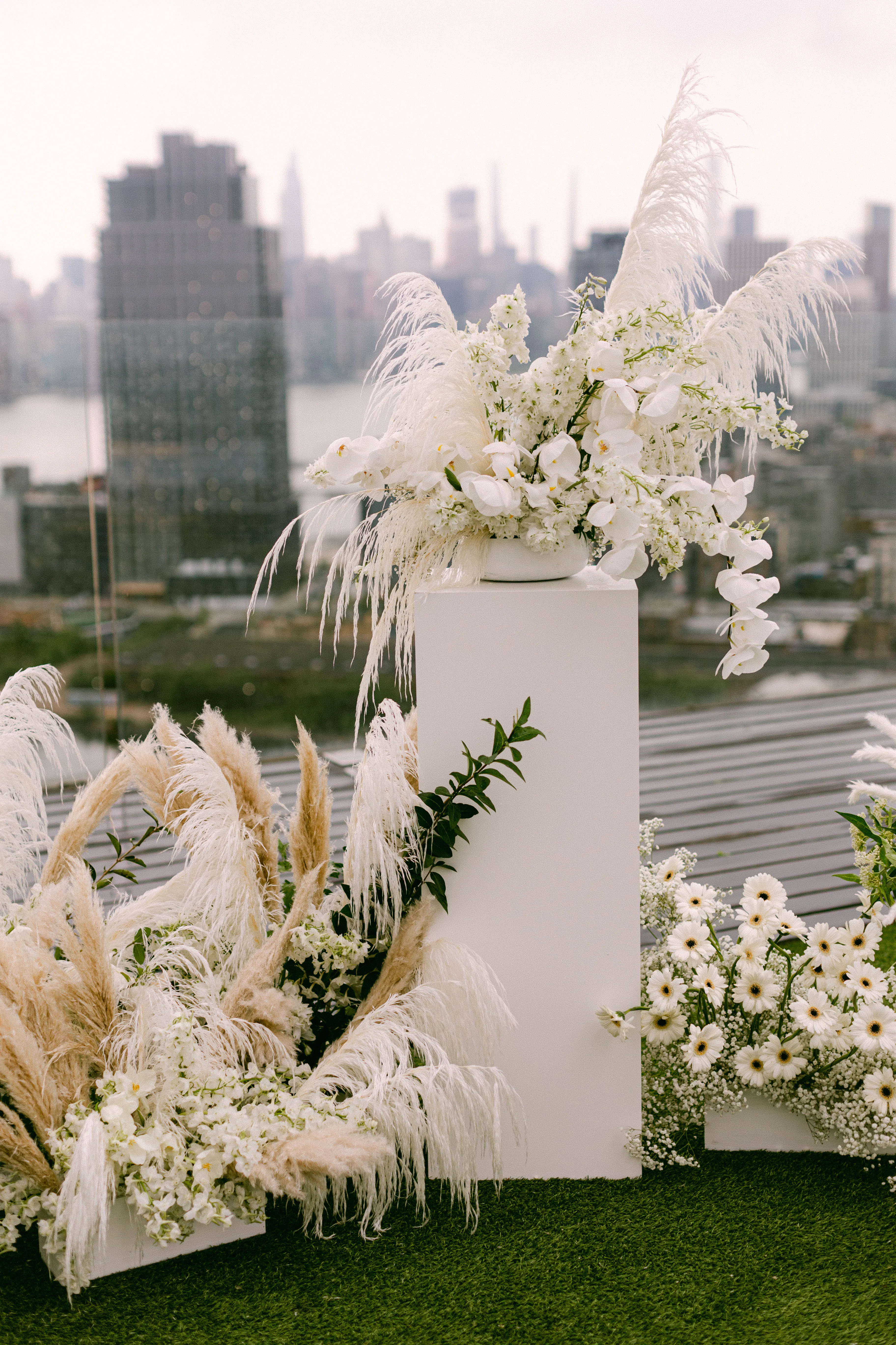 Close-up of the ceremony floral installation with pampas grass and white blooms above the skyline.