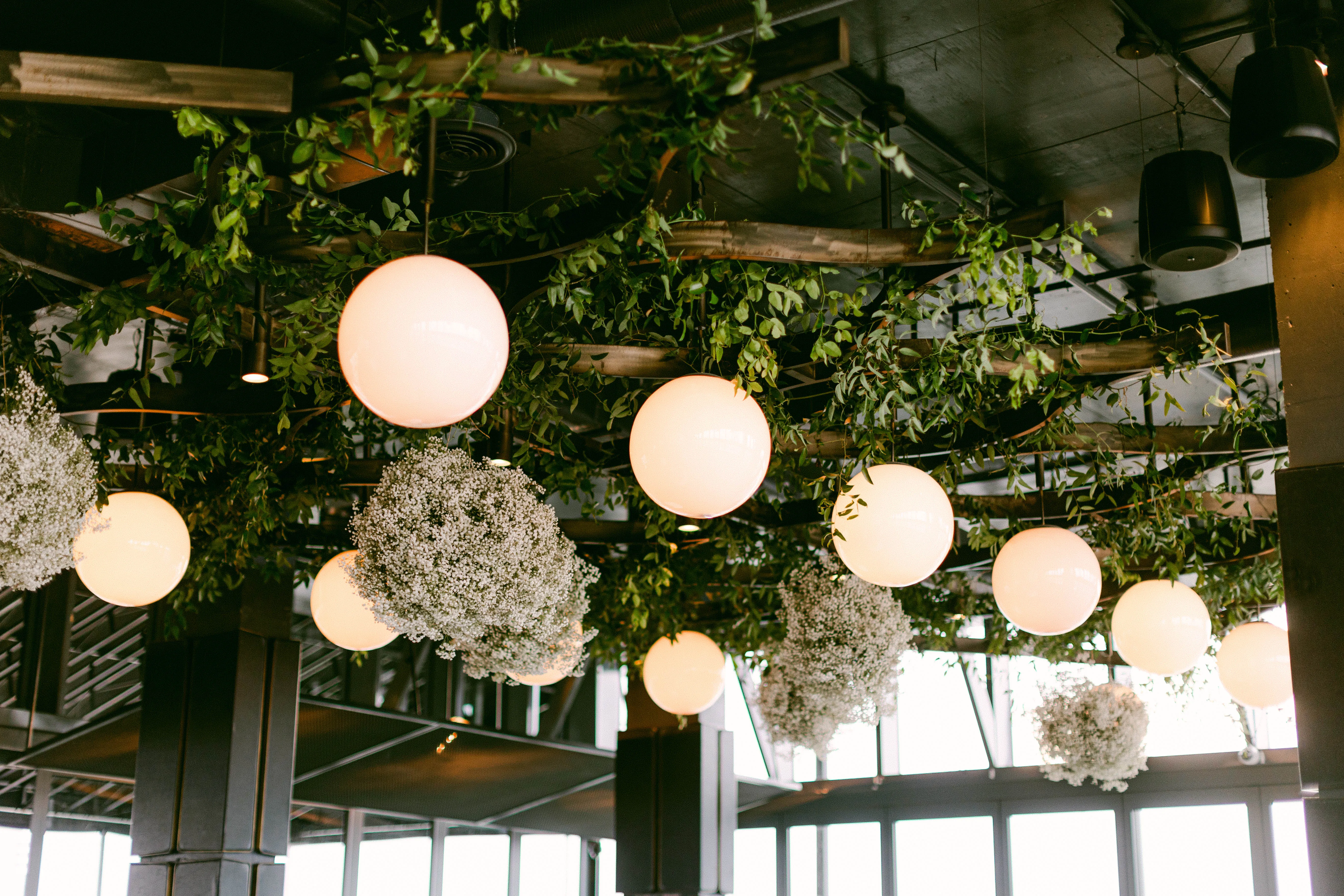 Hanging paper lanterns and baby's breath nestled in a greenery ceiling installation.