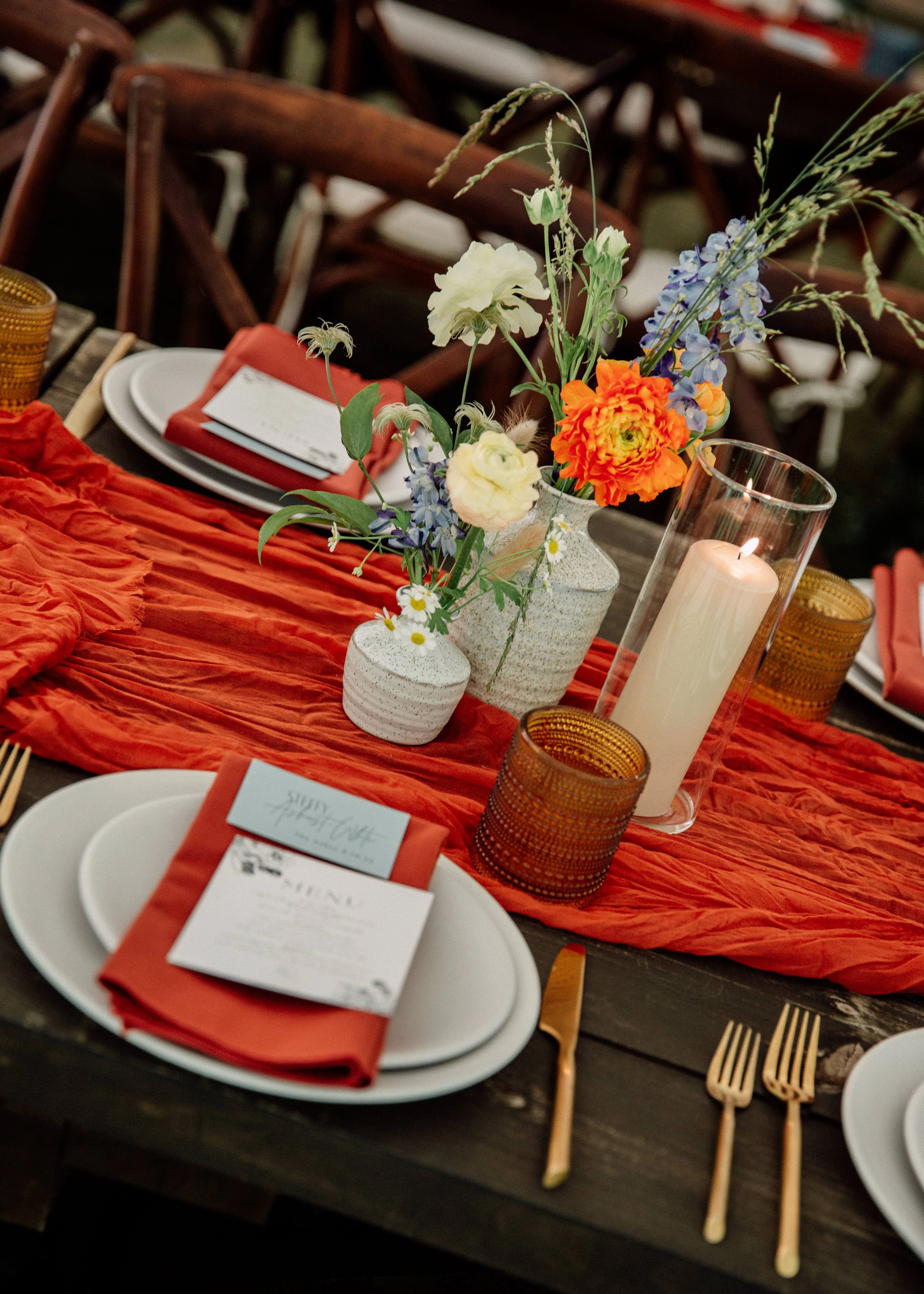Place setting detail with a red napkin and a blue, white, and orange wildflower centerpiece at Glen Falls House